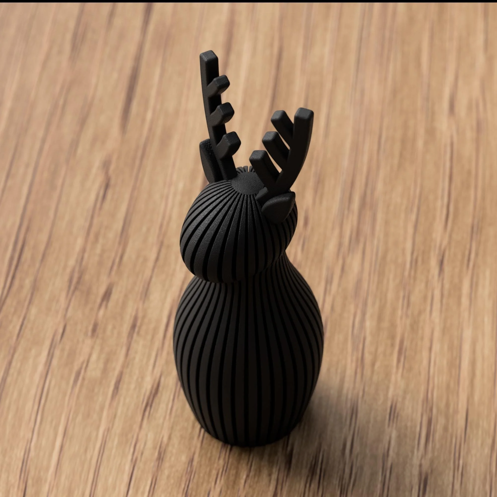 Schwarze Rentier Figur mit geriffelter Oberfläche und markantem Geweih, freigestellt auf Holz im klaren, modernen Weihnachtslook.