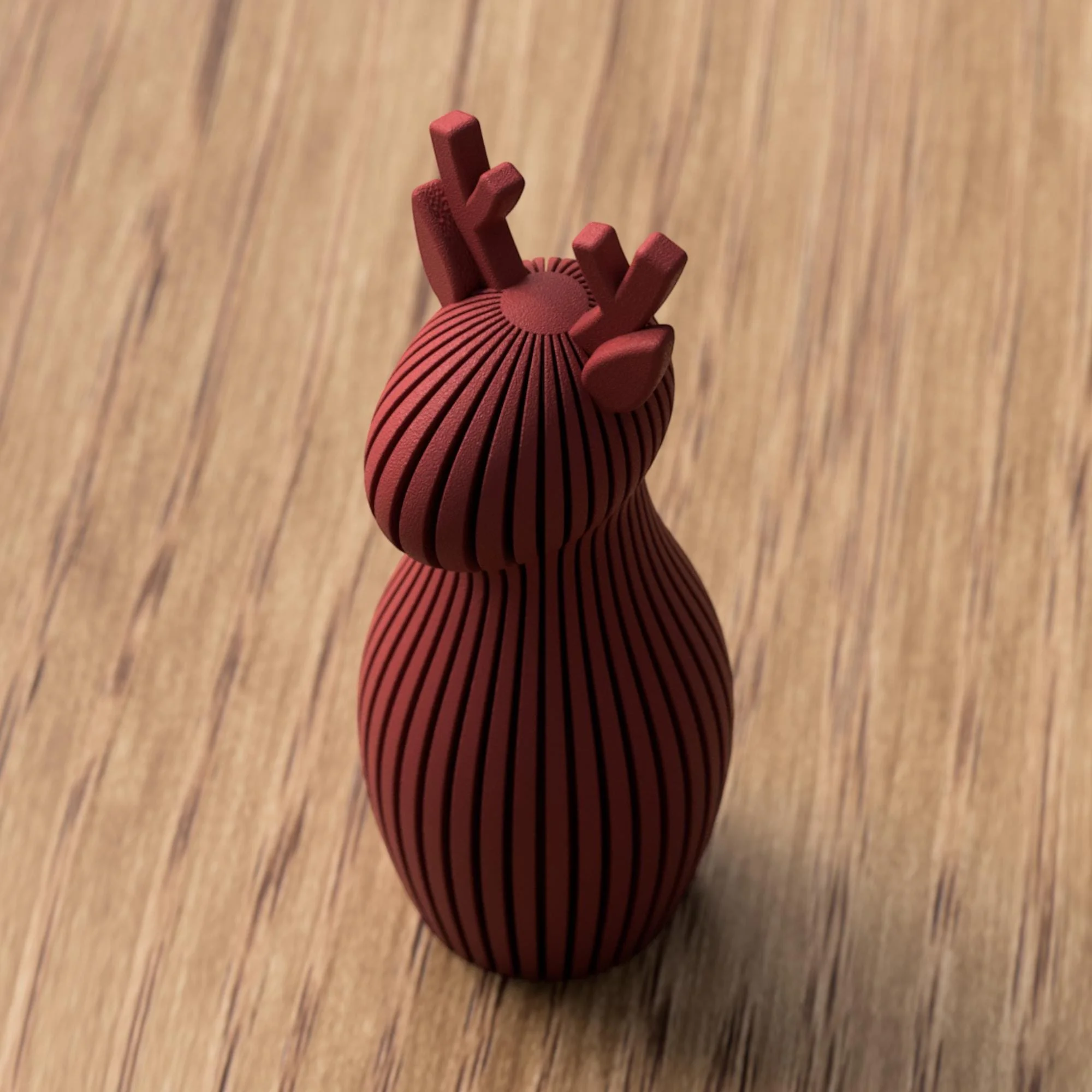 Weinrote Rentier Figur mit feiner Rillenstruktur und kurzem Geweih, einzeln auf Holz fotografiert als stilvolle Weihnachtsdekoration.