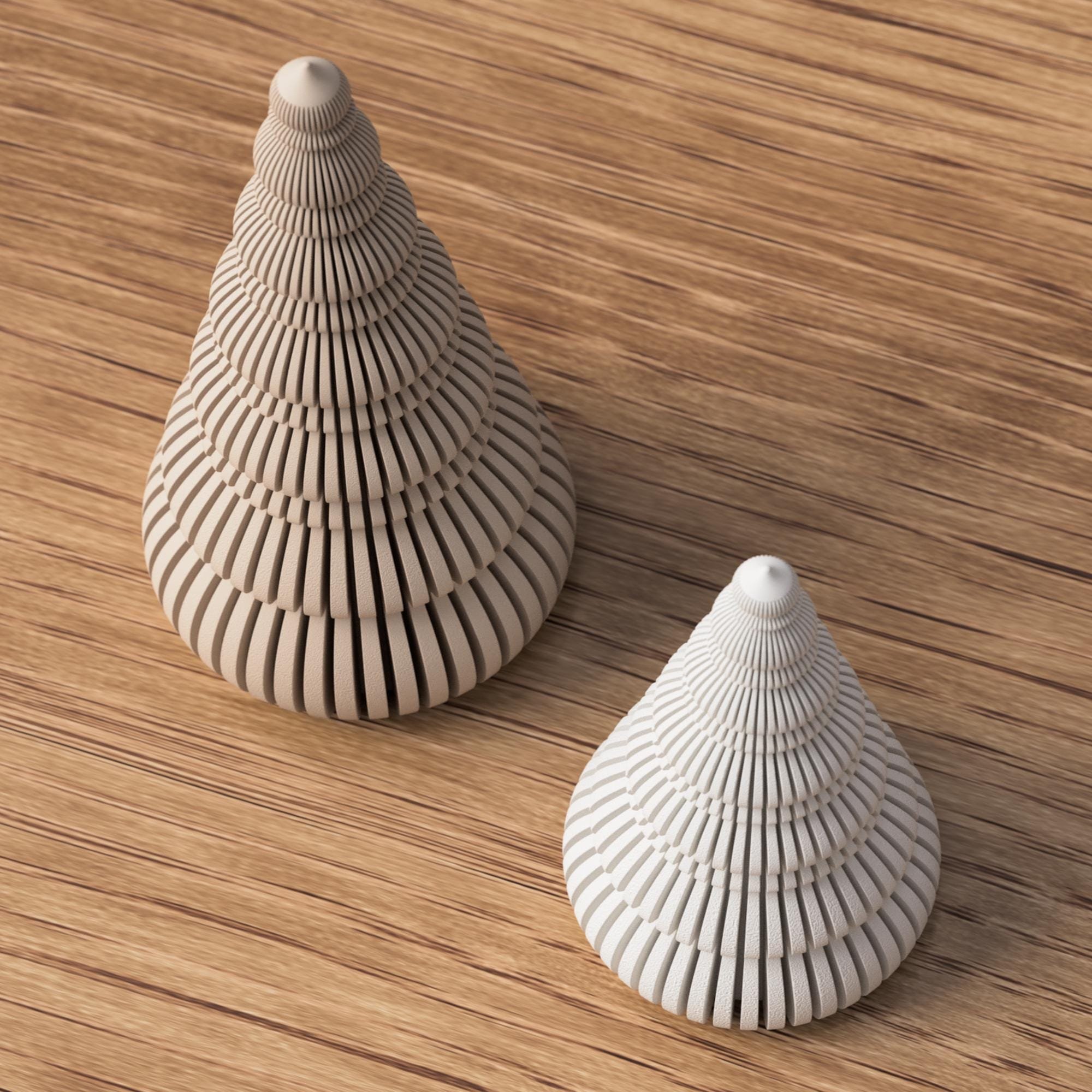 Zwei gerippte Deko-Weihnachtsbäume in Beige und Weiß auf Holzoberfläche, aus schräger Ansicht mit Fokus auf Form und Struktur.