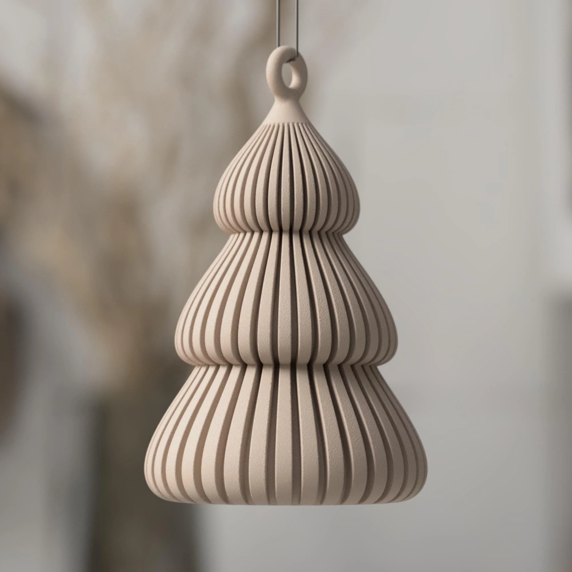 Beiger Christbaumanhänger in stilisierter Tannenform mit feinen Rillen und runder Aufhängung, freigestellt vor ruhigem, hellem Hintergrund.