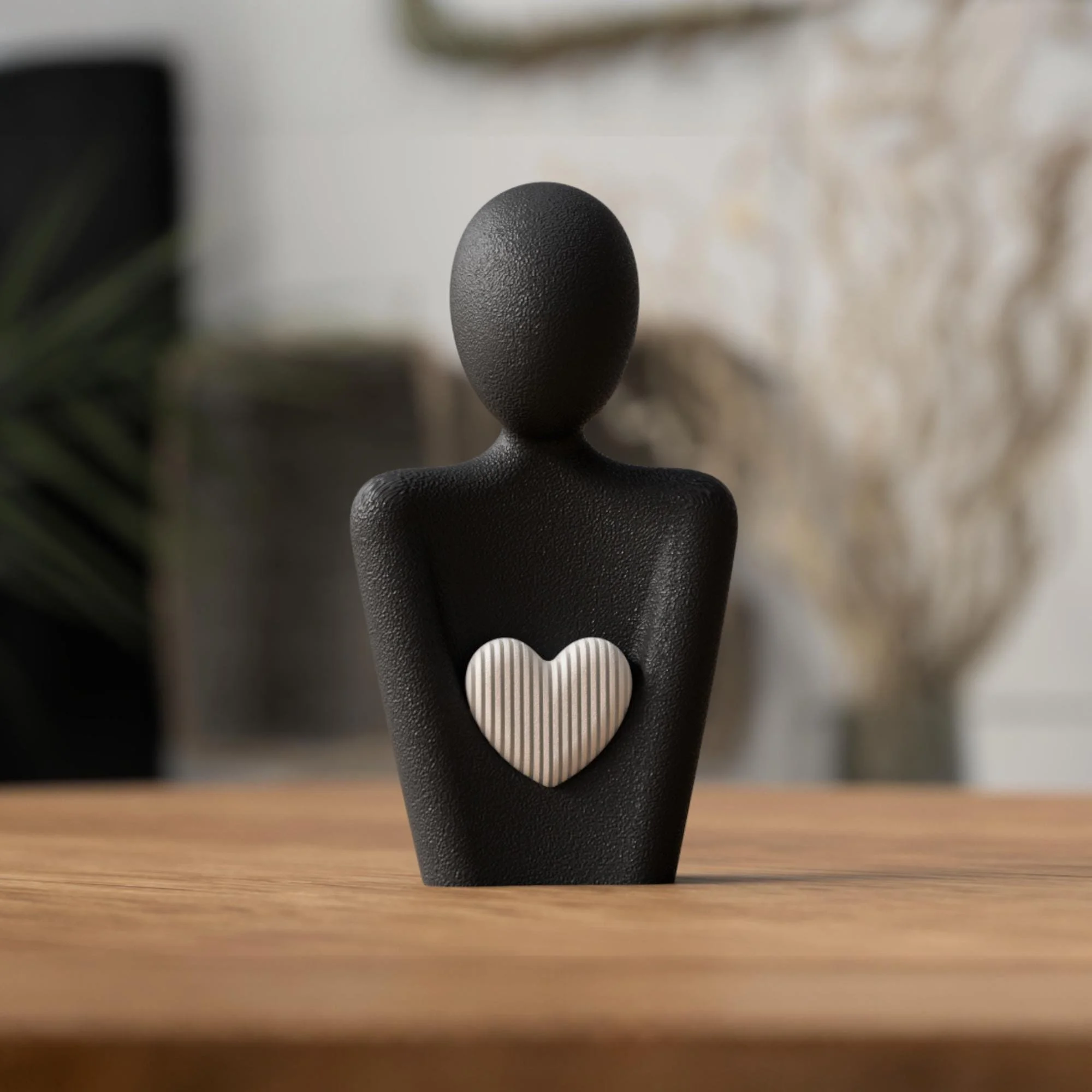 Schwarze Herzfigur mit hellem Herzdetail auf Holzfläche, moderne Deko im skandinavischen Stil als ruhiger Akzent für Wohnraum oder Büro.
