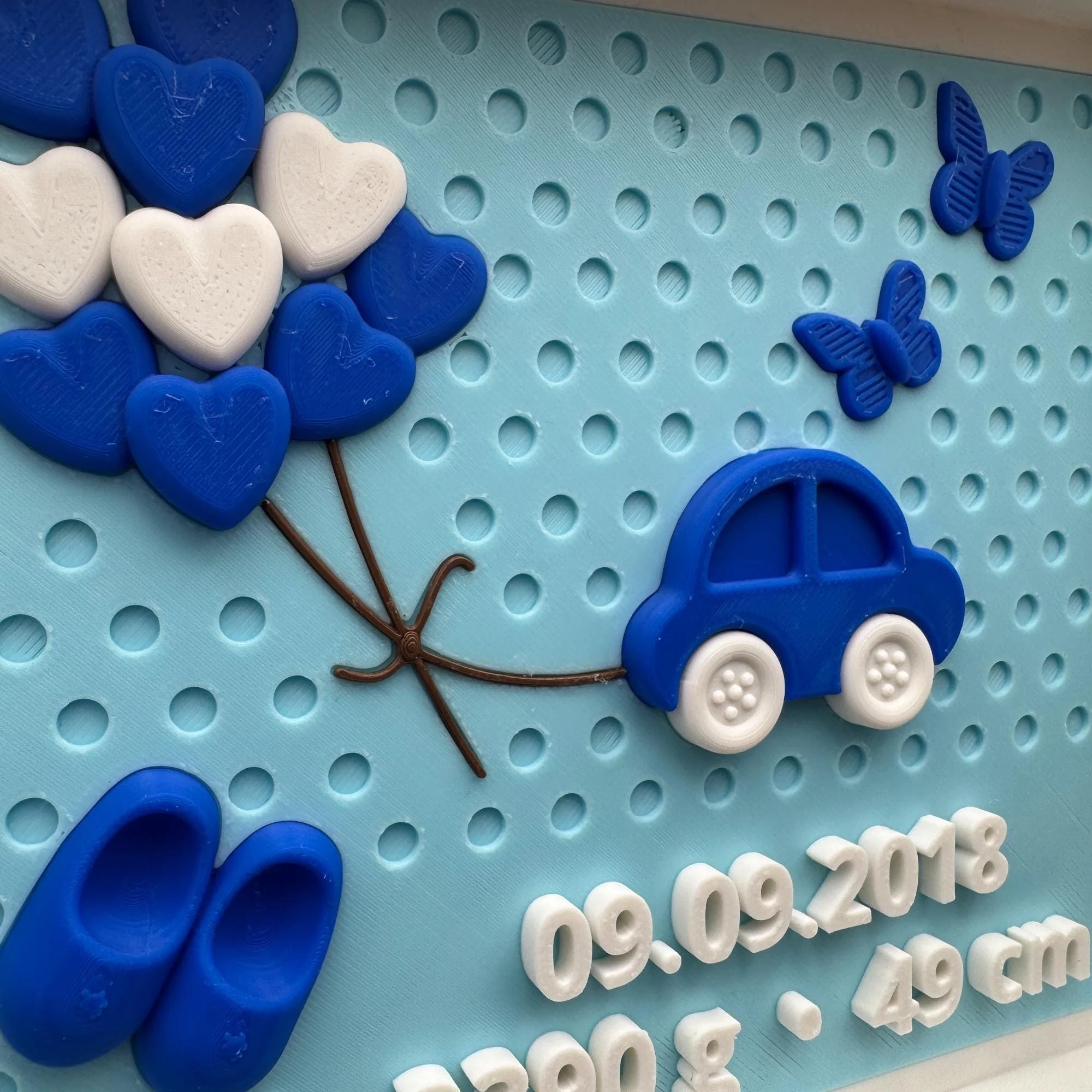 Nahaufnahme der Geburtstafel für Jungen mit blauem Auto, Wolkenballons, Schmetterlingen und sichtbaren Geburtsdaten als 3D-Elemente