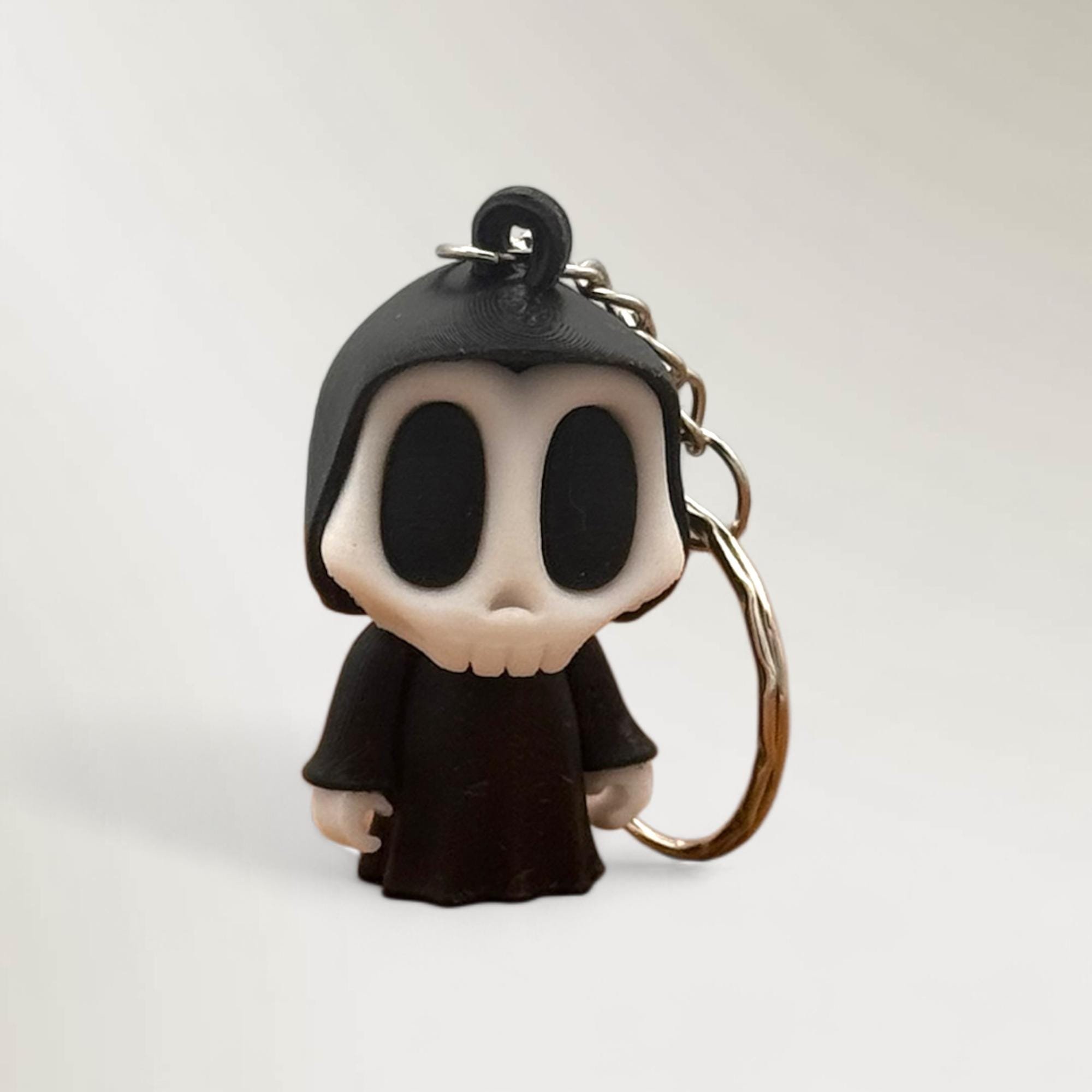 Schwarzer Skelett Schlüsselanhänger mit Metallring vor hellem Hintergrund.