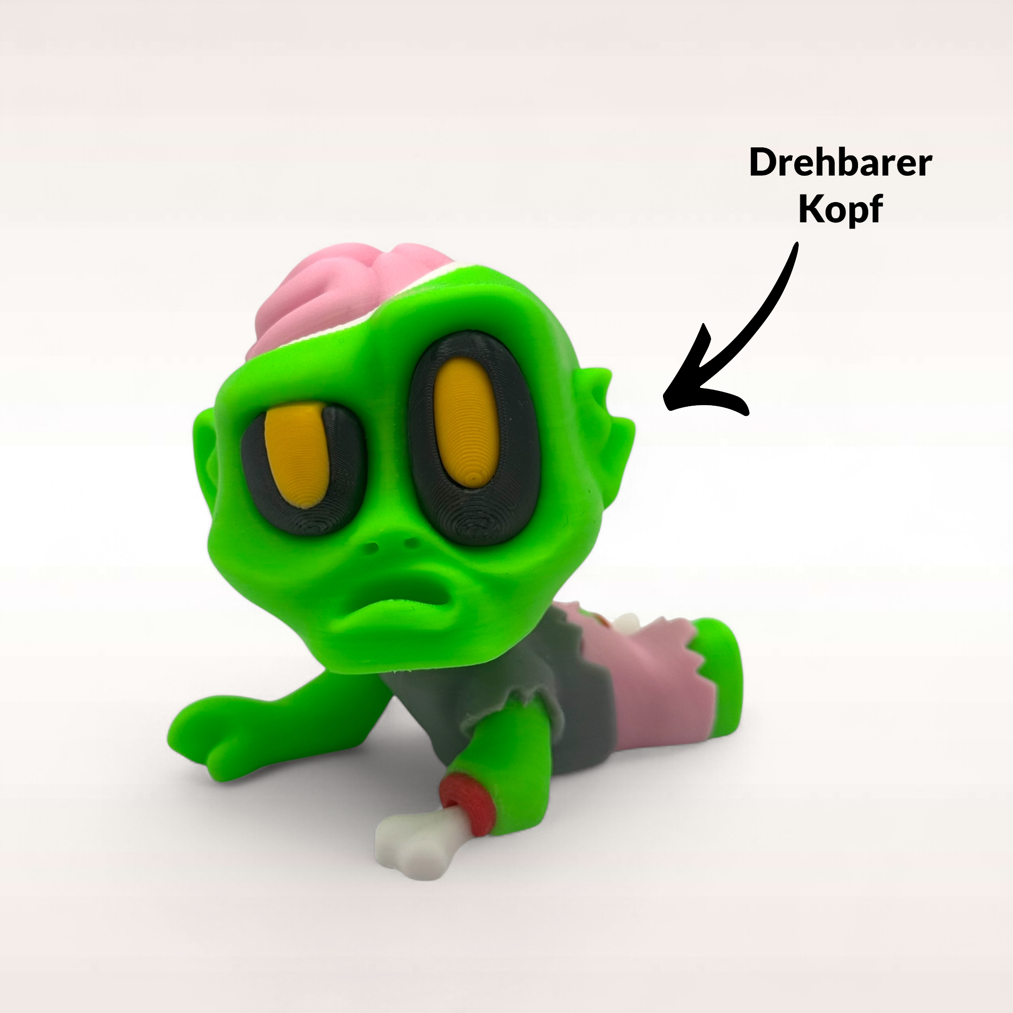 Liegende Mini-Zombie-Figur mit freiliegendem pinkem Gehirn und Hinweis auf drehbaren Kopf für Horror- und Halloween-Deko.