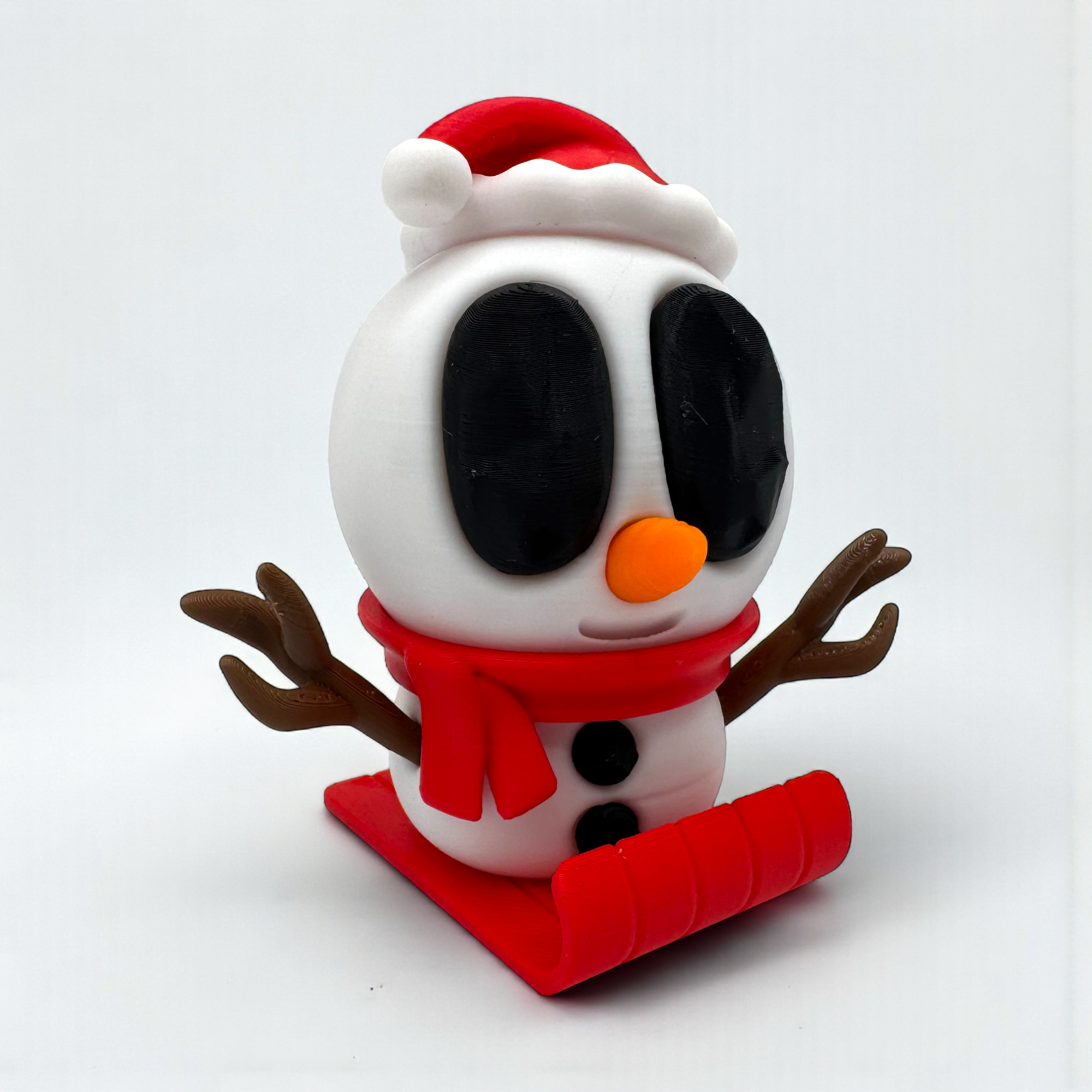 Rote Schneemannfigur mit Bommelmütze auf rotem Schlitten, frontal auf hellem Hintergrund und mit ausgestreckten Astarmen gezeigt.