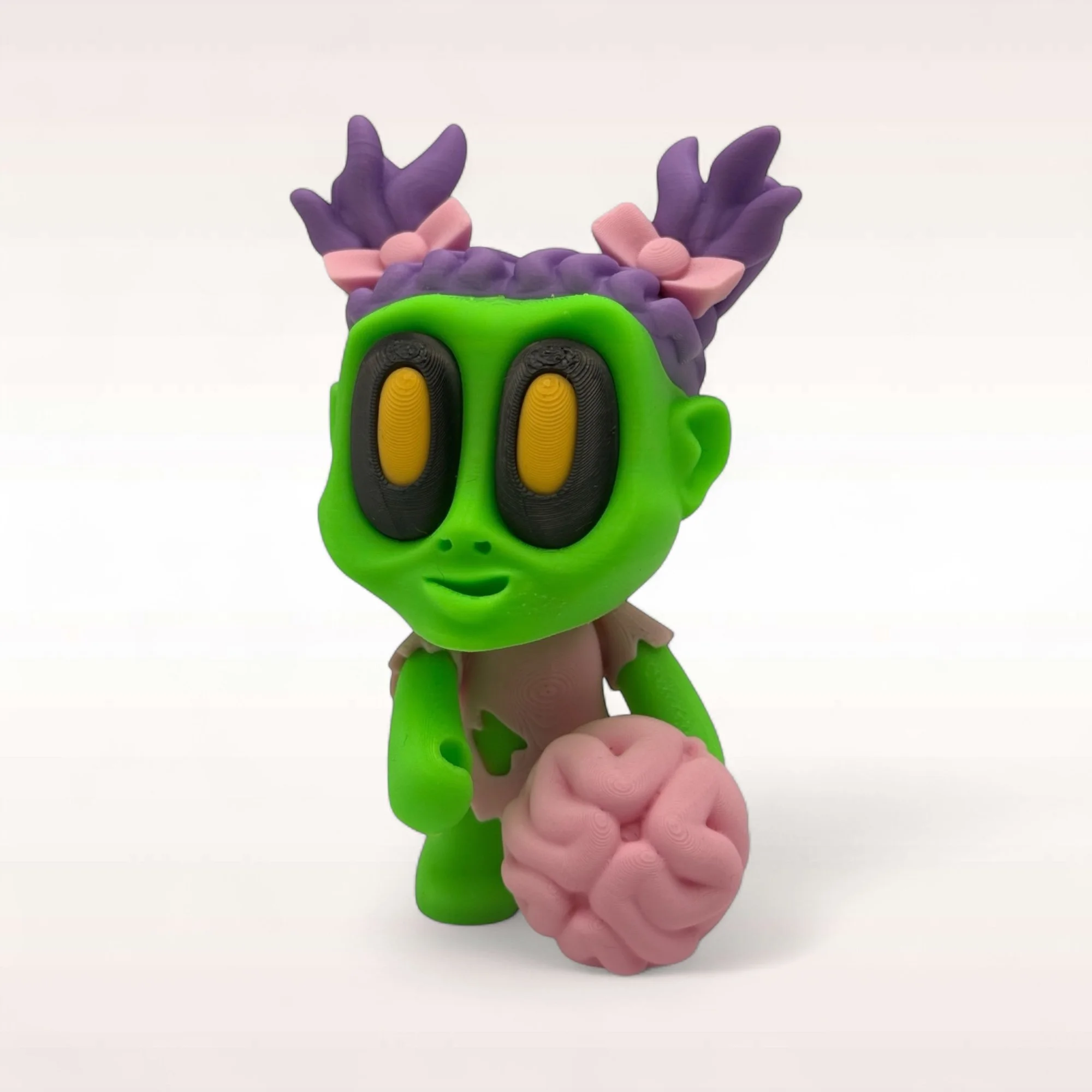 Stehende Mini-Zombie-Figur in Grün mit lilafarbenen Haar-Details und pinkem Gehirn als markanter Blickfang für Halloween.