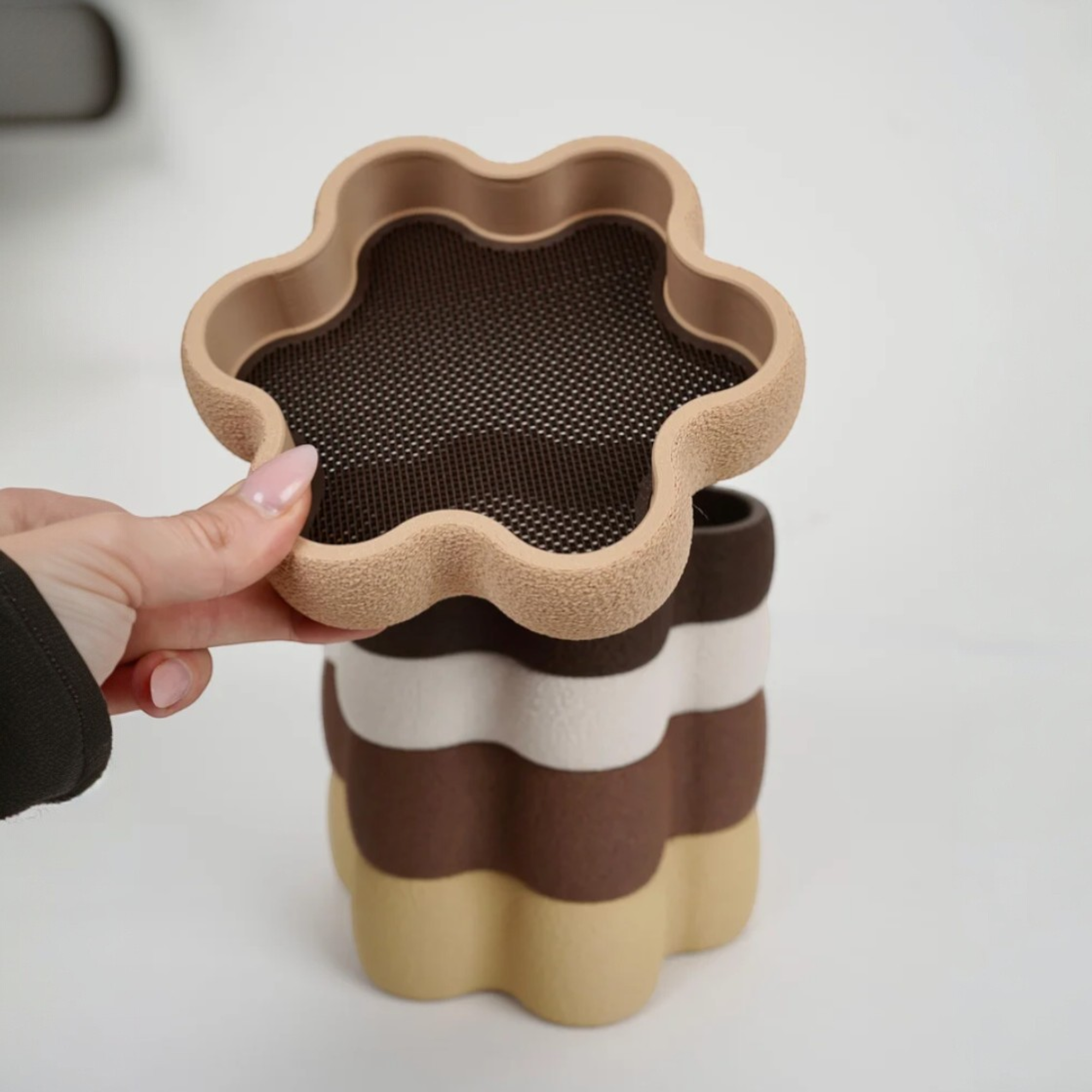 Blumenförmige Schmuckschale in Braun und Beige als Nahaufnahme in der Hand, mit weicher organischer Form und farblich abgestimmter Einlage.