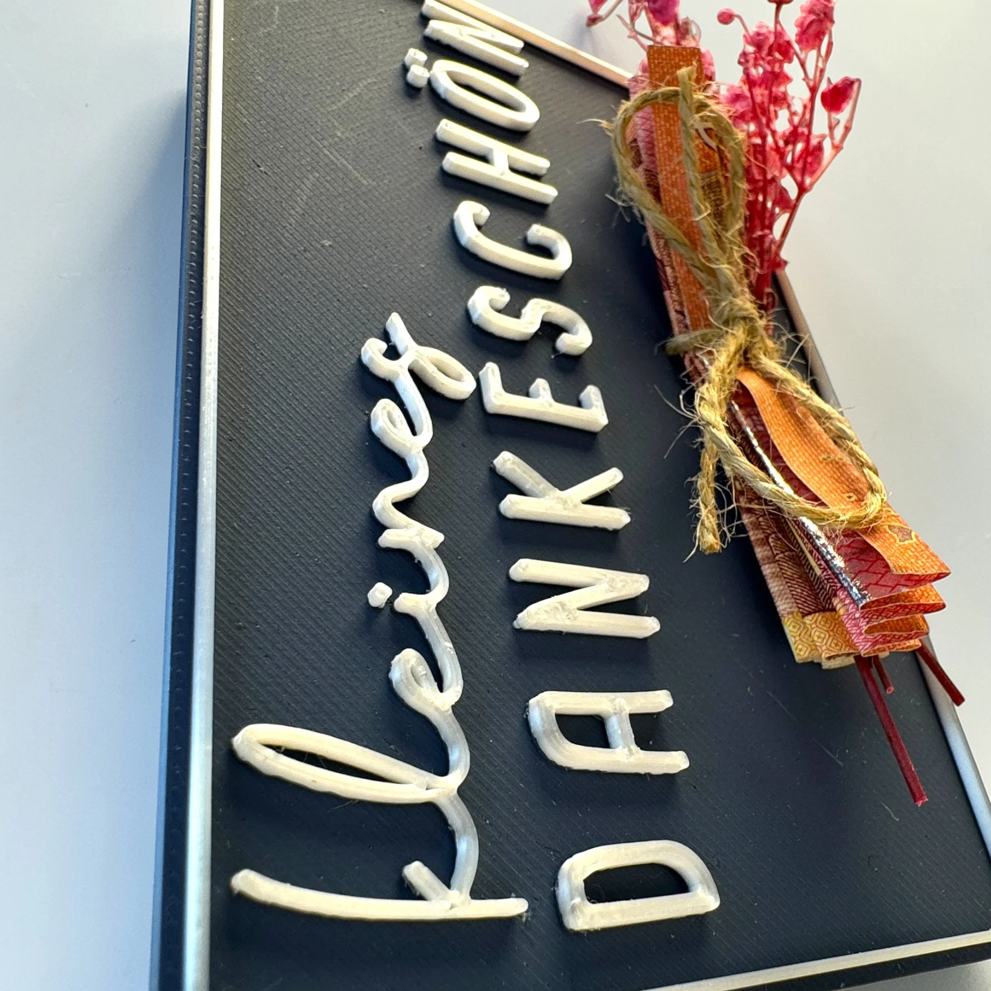 Detailansicht der Variante kleines Dankeschön mit großem Schriftzug, gebündelten Trockenblumen und gerolltem Geldschein an der Kartenfront