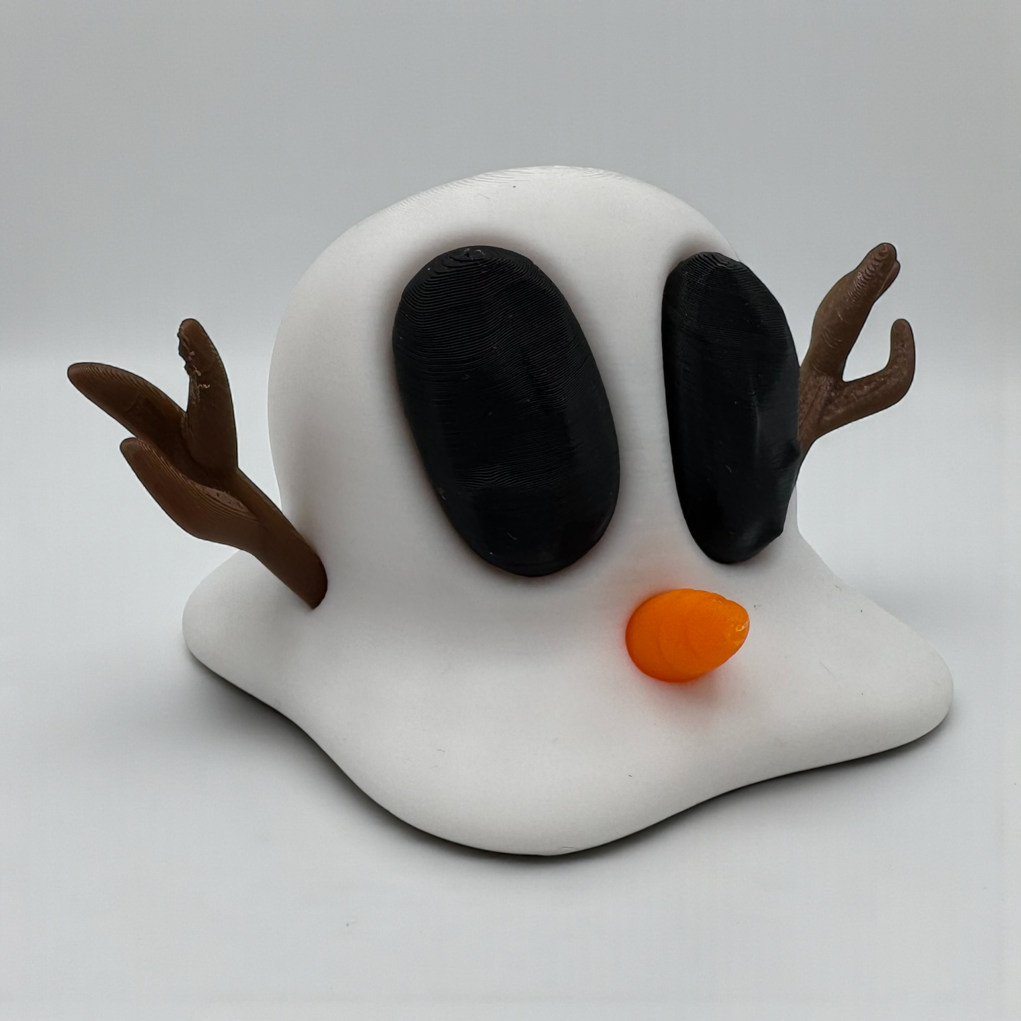 Geschmolzene Snowblobs Mini-Figur mit Karottennase und Astarmen auf hellem Hintergrund, flach geformt und humorvoll gestaltet.