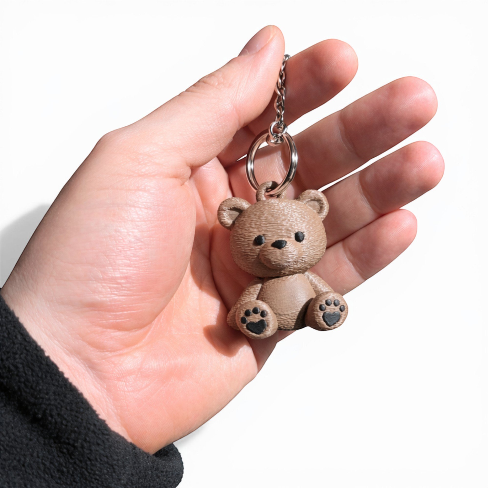Brauner Teddy Schlüsselanhänger mit klassischen Augen in einer Hand, kleiner Anhänger mit Metallkette für Schlüsselbund, Tasche oder Rucksack.