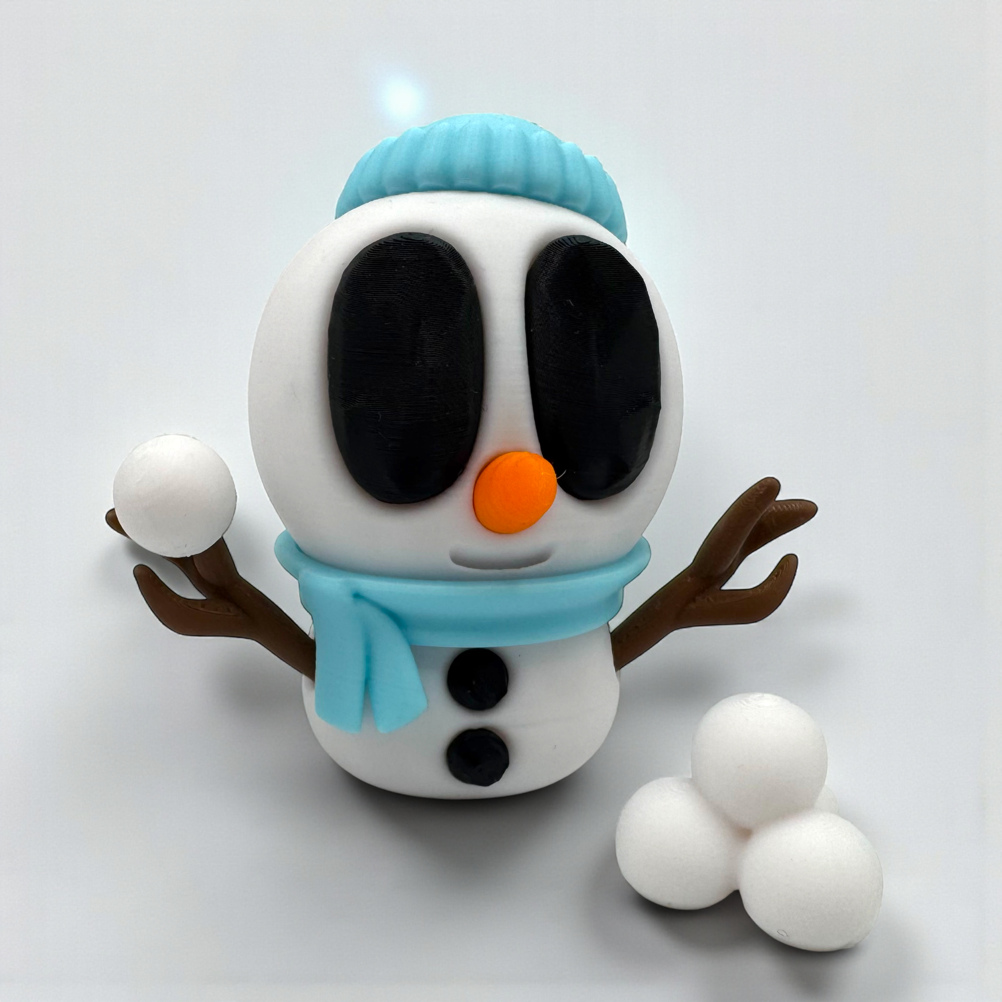 Blaue Schneemannfigur mit türkisfarbener Mütze und drei Schneebällen auf hellem Hintergrund, kompakt und verspielt arrangiert.