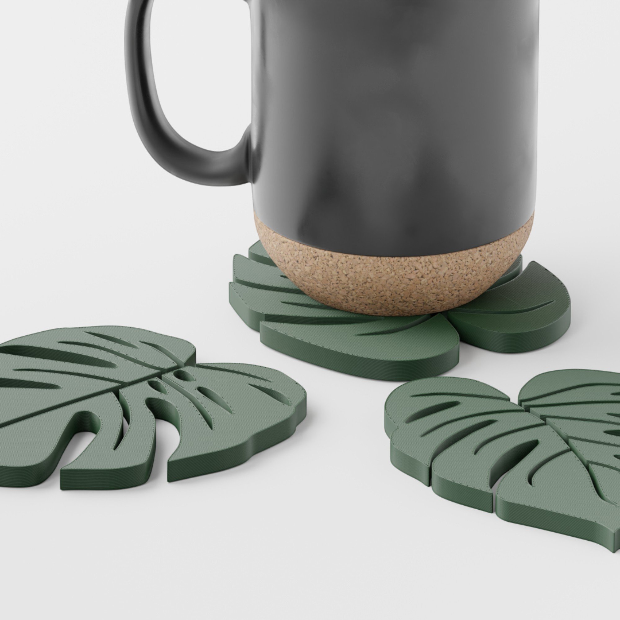 Detailansicht des Monstera-Untersetzers mit schwarzer Tasse, sichtbarer Blattstruktur und weiteren grünen Untersetzern im Hintergrund