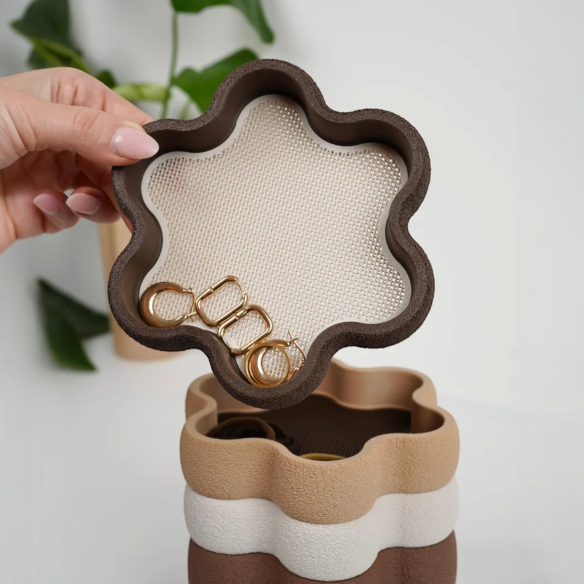 Hohe Schmuckschale in Blumenform mit geöffnetem Oberteil, darin Ringe und Ketten als praktische Aufbewahrung für Schmuck auf Kommode oder Nachttisch.