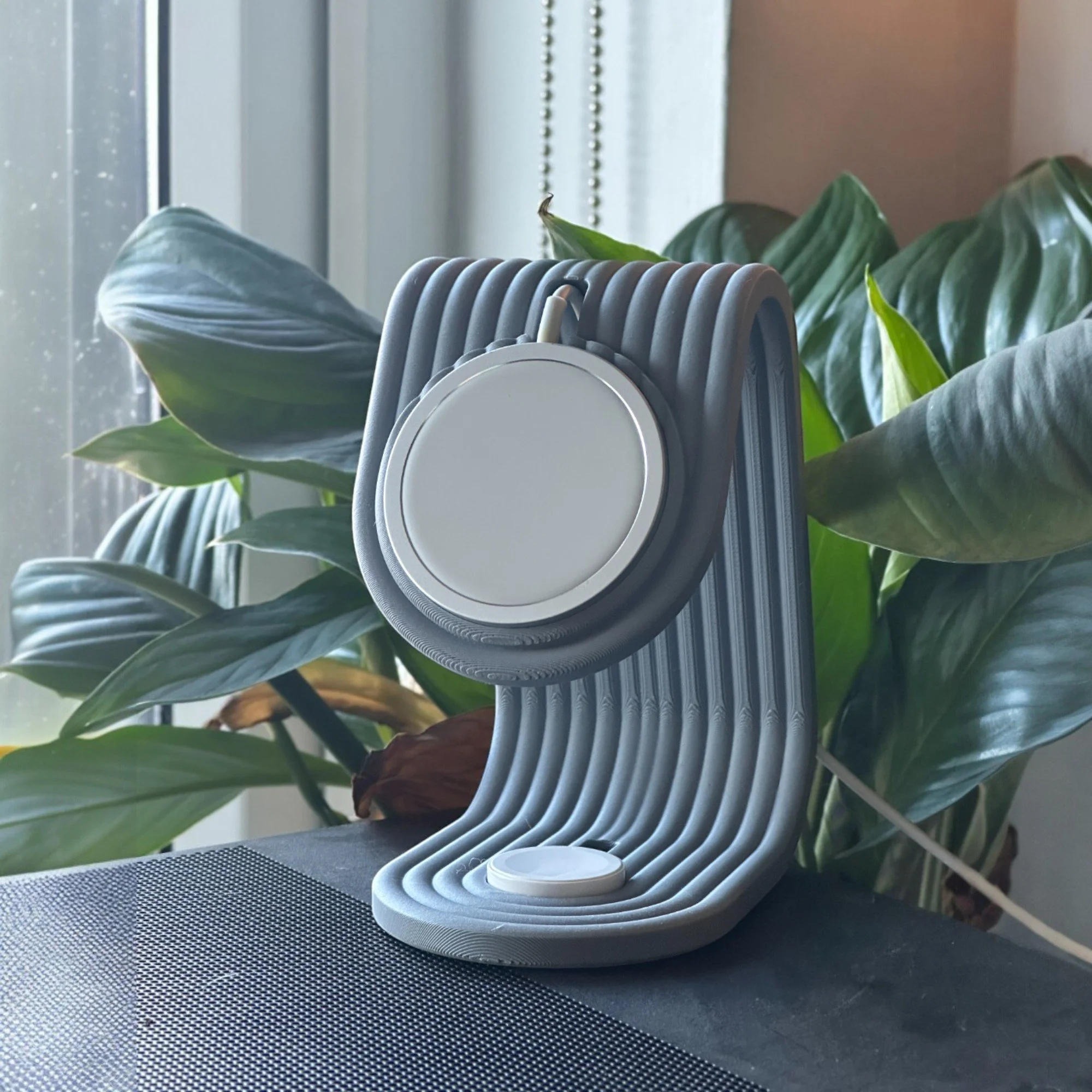 2-in-1 MagSafe Halterung in grau-weißer gestreifter Farbvariante mit runder Aufnahme für iPhone und Apple Watch, dekorativ ins Wohnumfeld gestellt