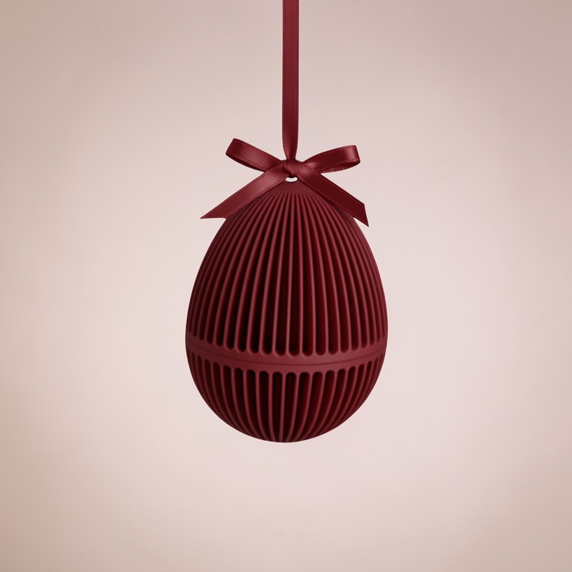 Bordeauxrotes Osterei zum Befüllen mit gerippter Oberfläche und Schleife, dekorativ aufgehängt als Anhänger für Osterstrauch oder Frühlingszweige.
