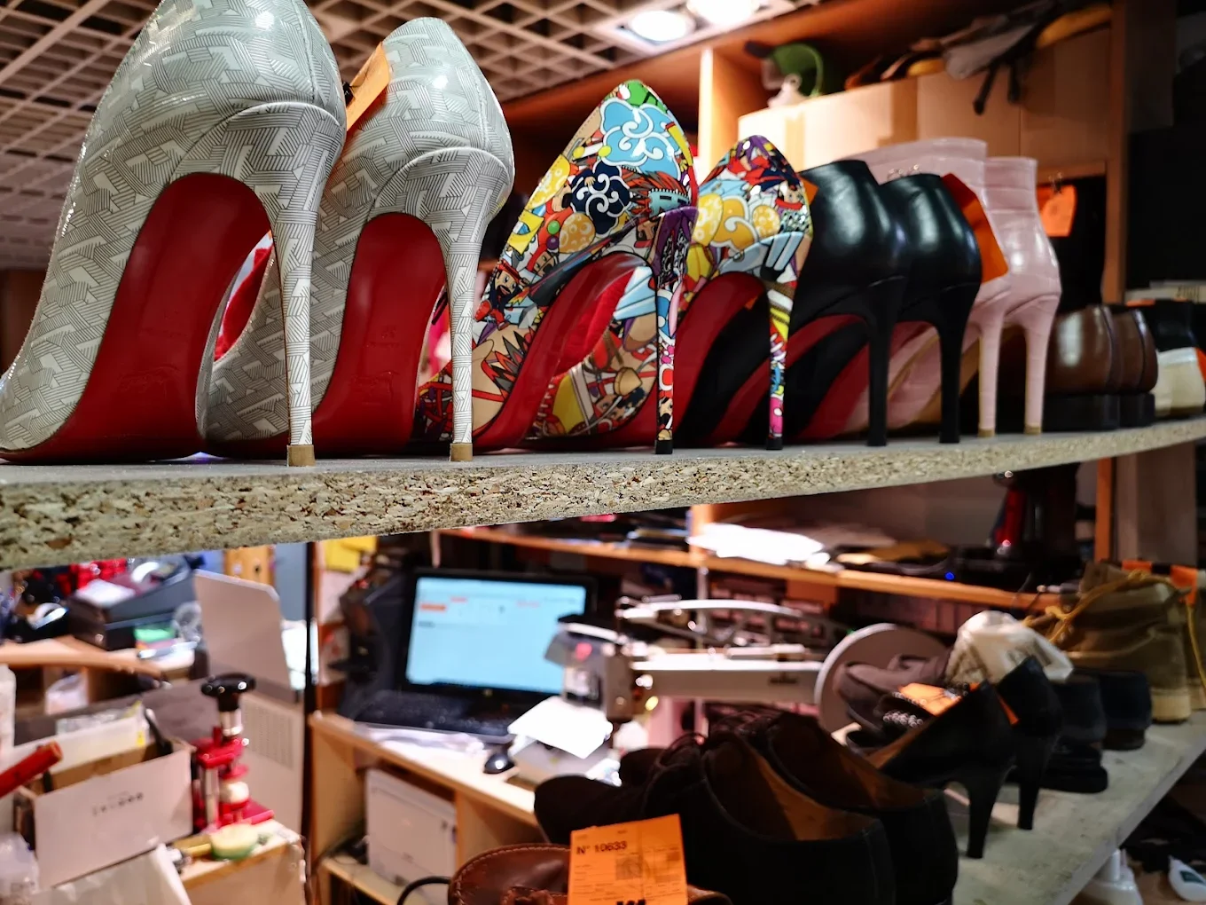 Chaussures haut de gamme sur une étagère, comprenant des talons à motifs colorés, noirs, roses, et d'autres, dans une boutique de chaussures.
