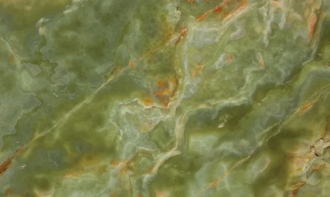 Close-up of green and orange marble stone surface with natural patterns and textures.