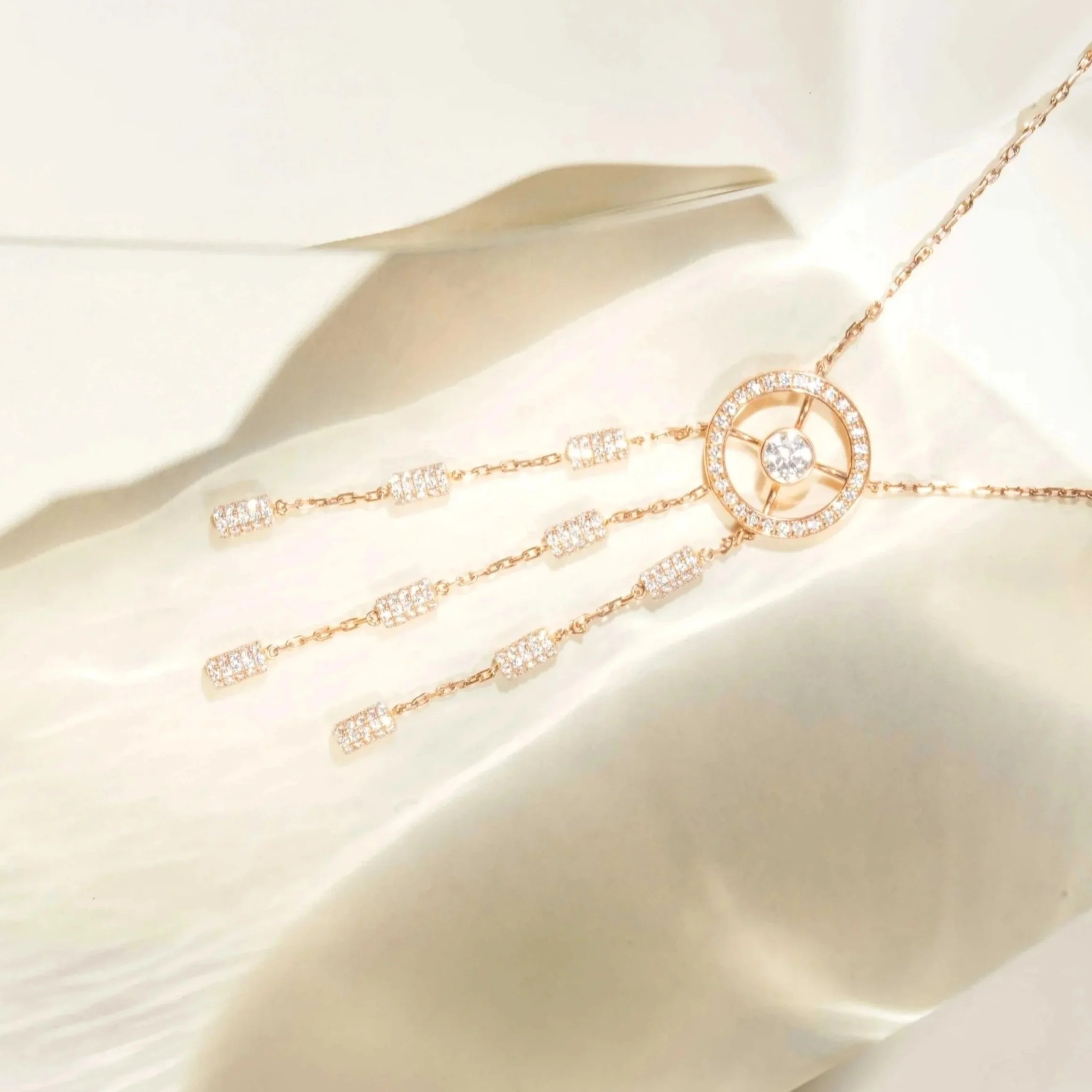 Close-up of a gold necklace with a circular pendant encrusted with small diamonds, set against a light background.