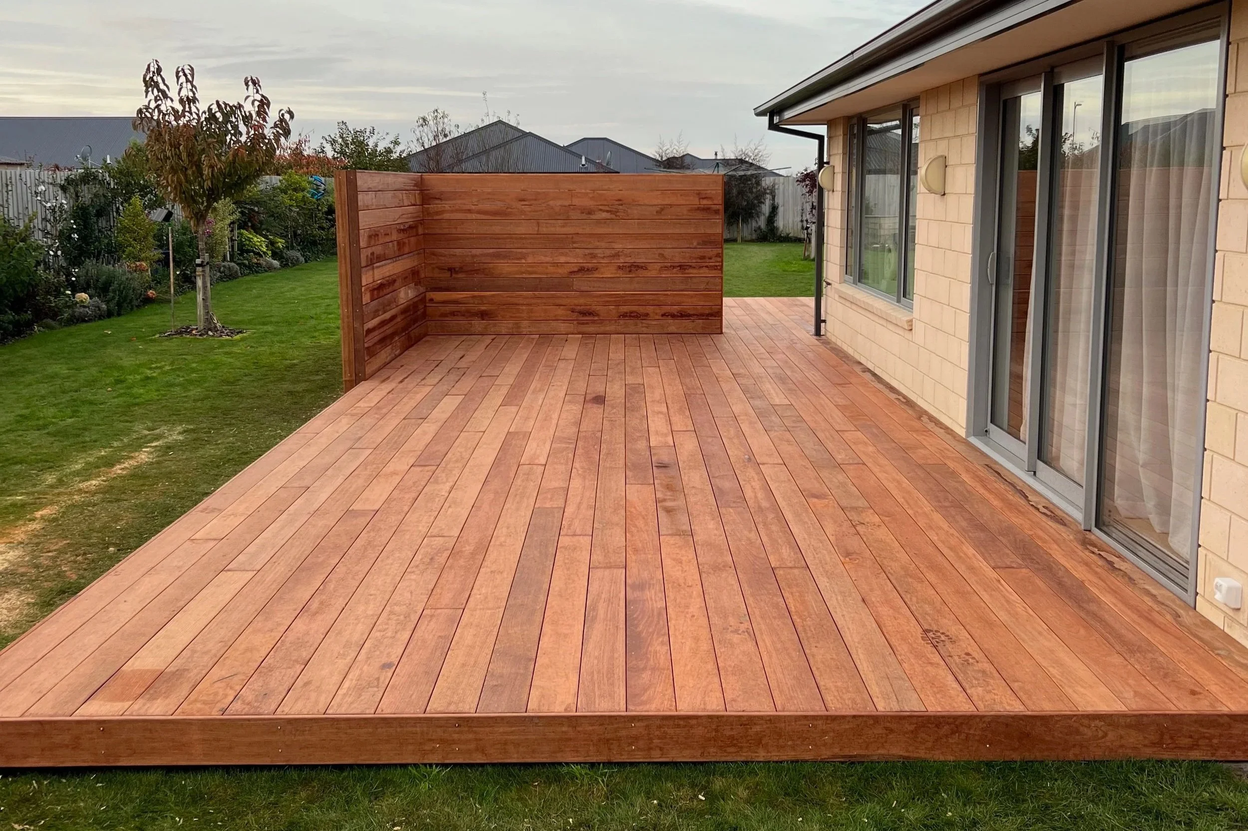 This custom deck for a home is Christchurch features a corner wall, creating a wind barrier for the outdoor entertainment space and adding a refined, cosy look to the new deck area.