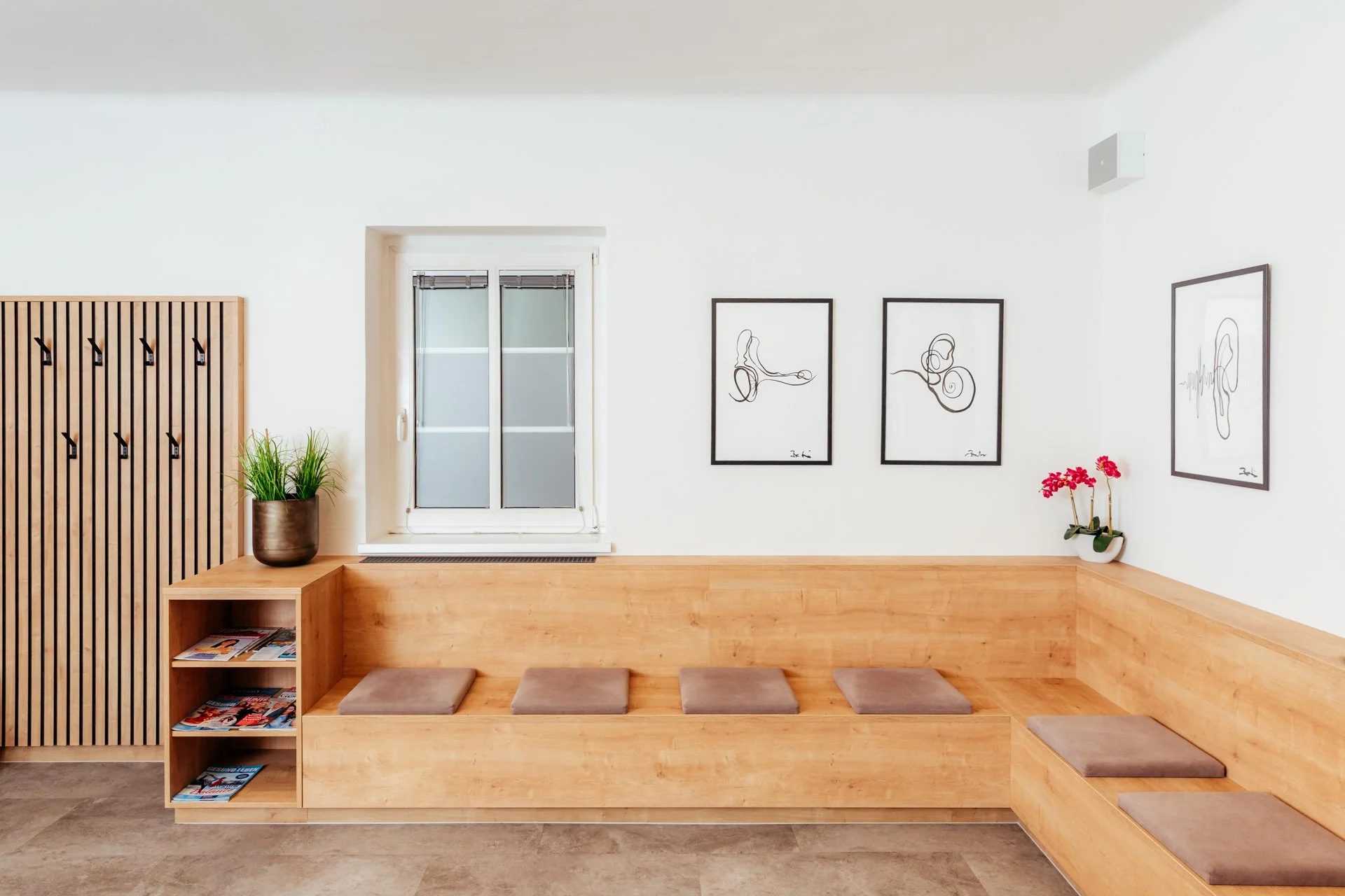 warten Raum mit Holzvorrichtung, farbigen Kissen, Pflanzen, Fenster, Kunstwerke an der Wand