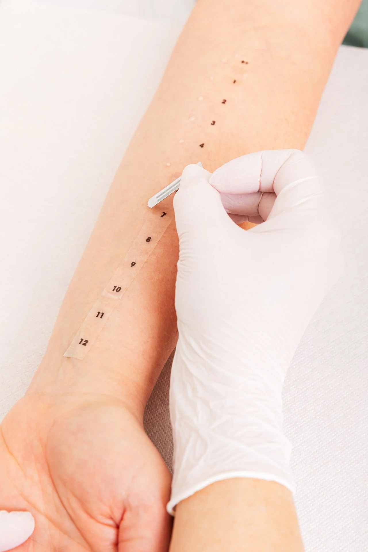 Eine Person erhält eine Blutentnahme am Unterarm, mit einem Venenmessgerät an der Armbeuge, während eine andere Person die Vene mit einer Kanüle durchsticht.