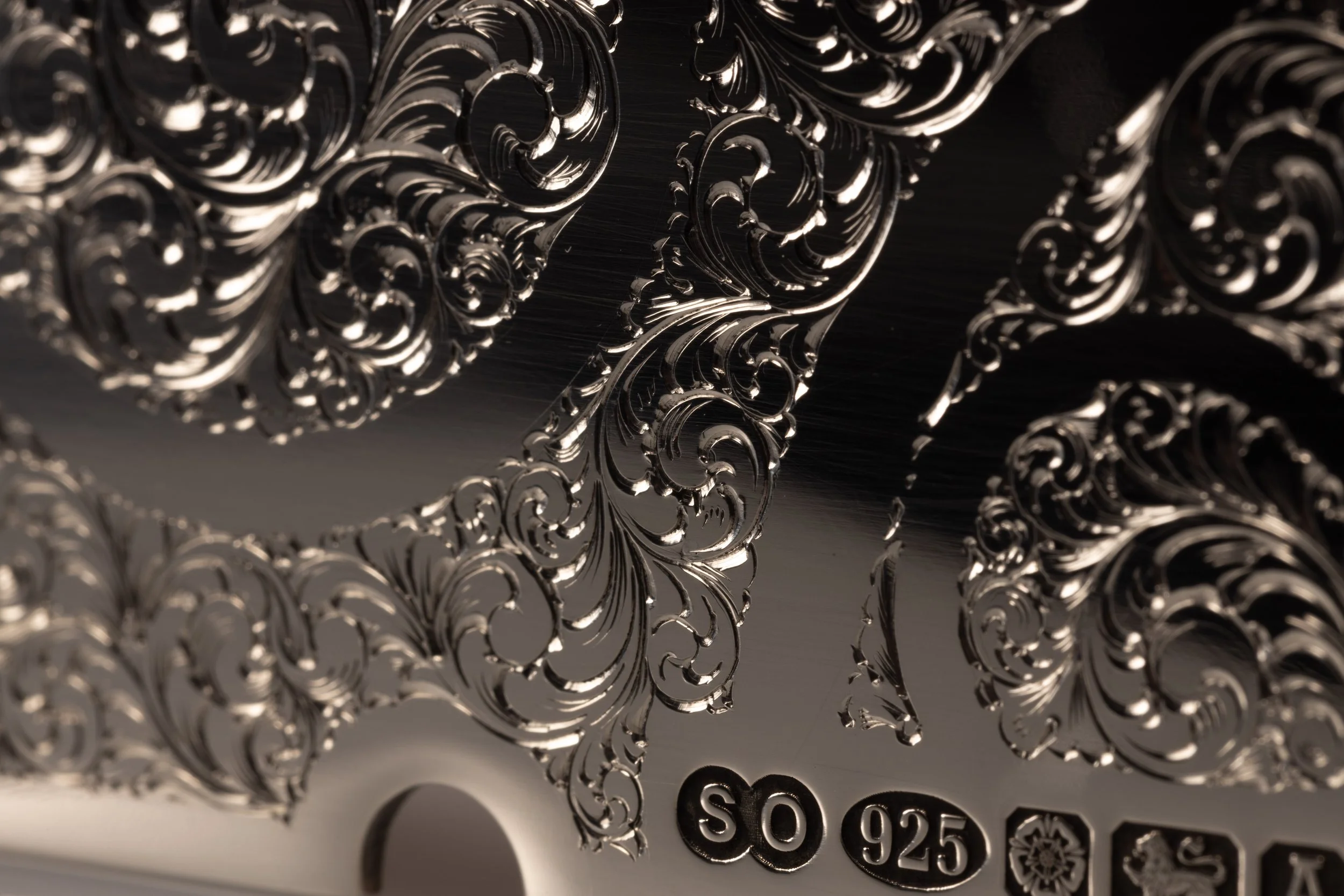 An image of a sterling silver belt buckle with hallmarks and engraved with a filigree design by silversmith Harry Stokes.