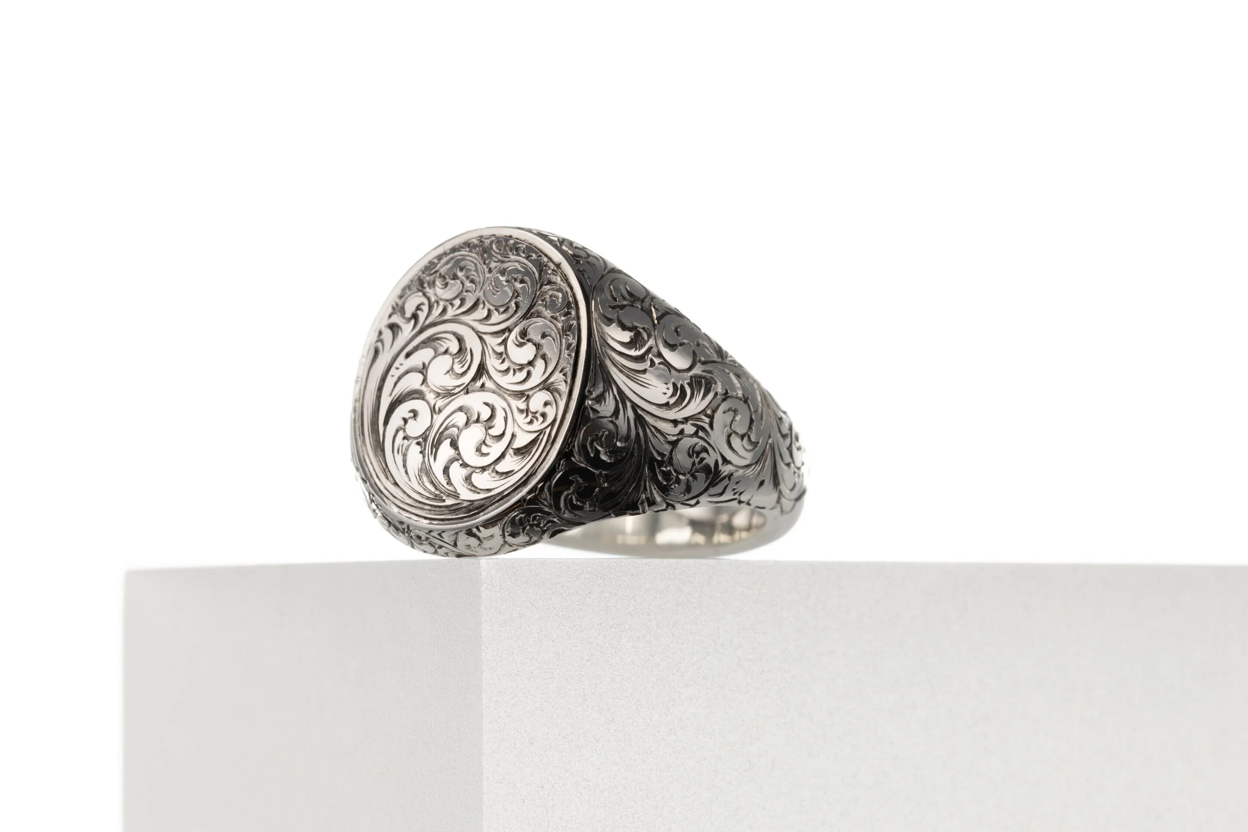 A sterling silver signet ring made by silversmith Harry Stokes with filigree engraving detail.