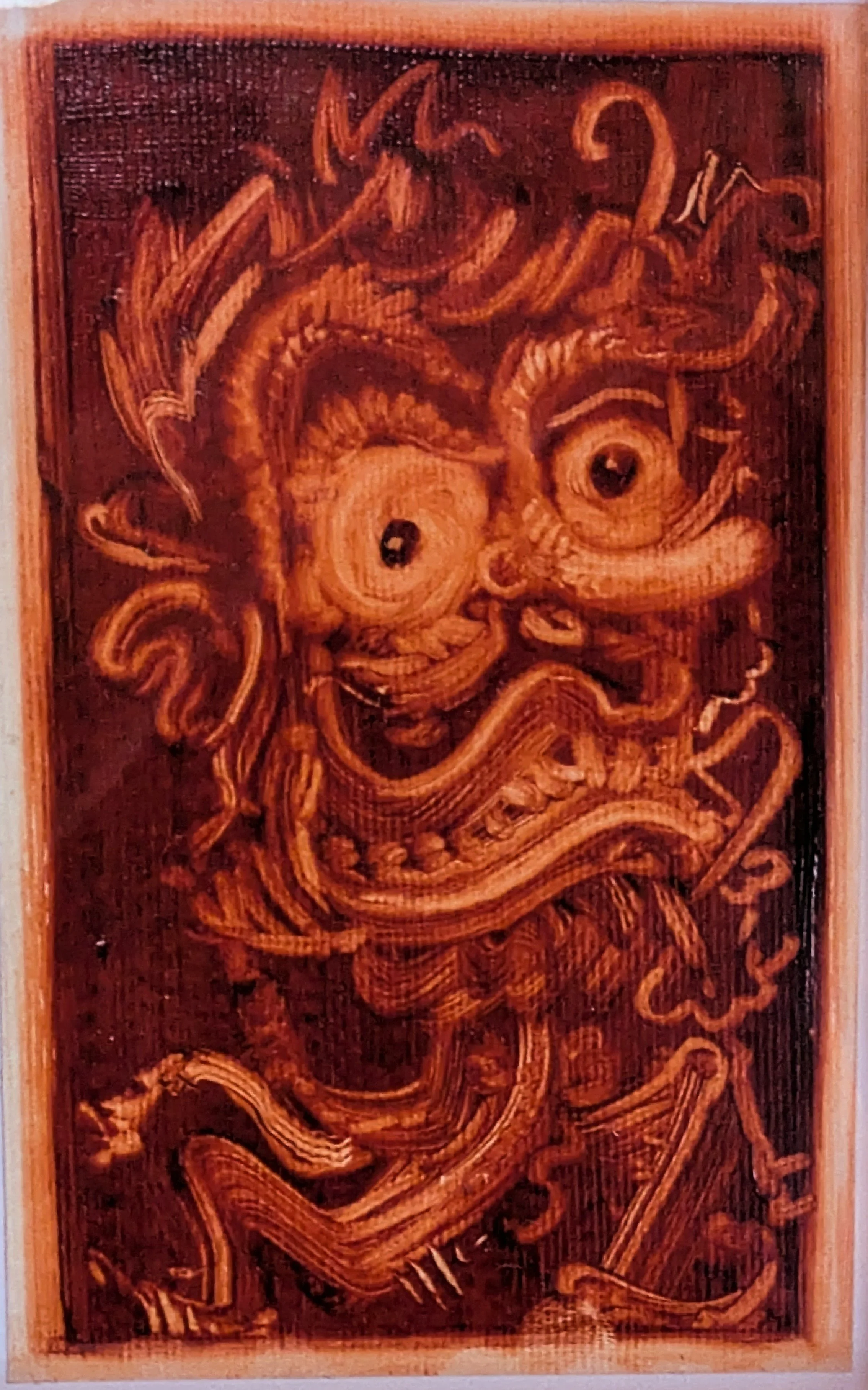 Wooden carved panel featuring a warrior holding a large weapon with a shield, surrounded by intricate patterns and designs.