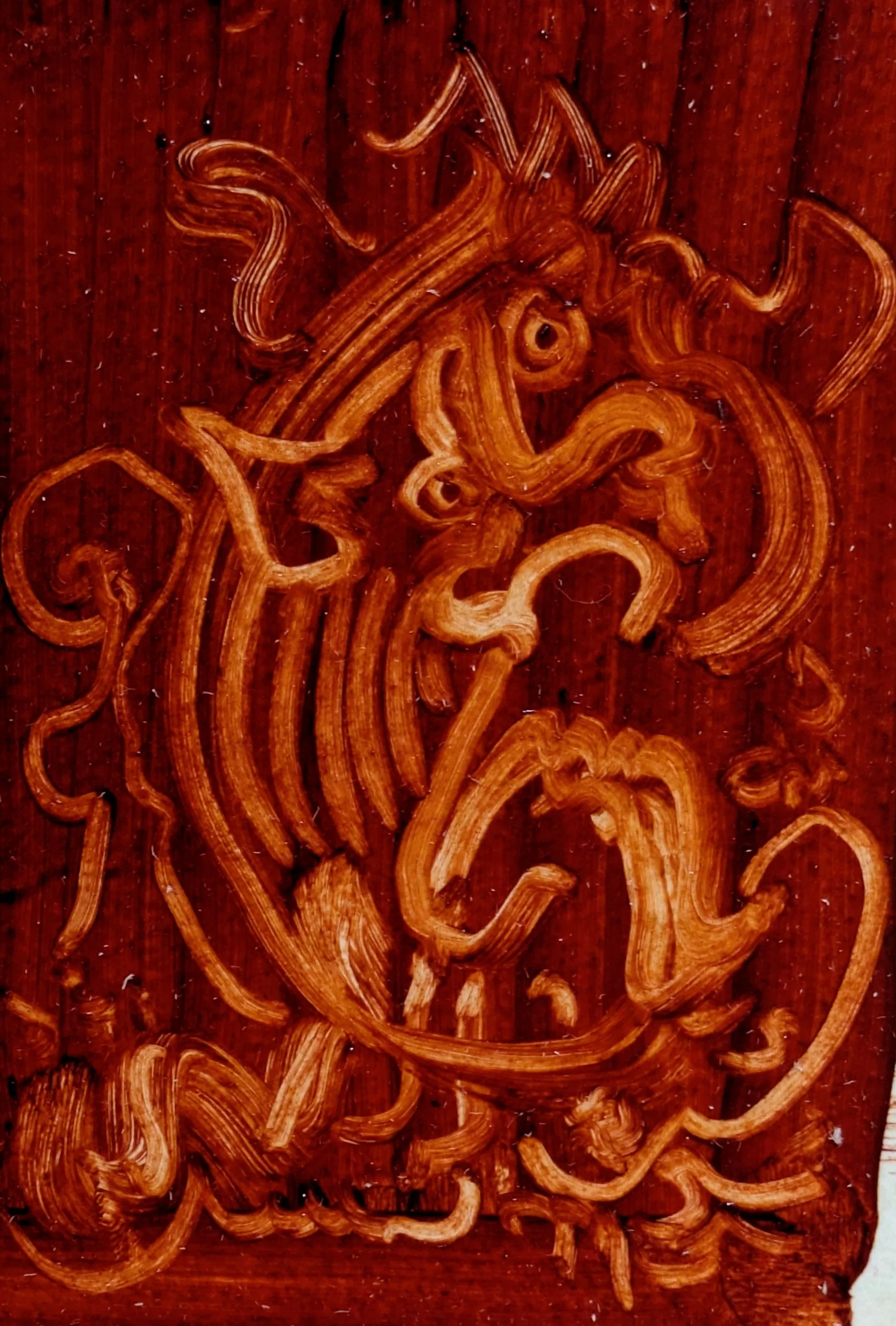 Close-up of an intricate wooden carving with swirling and intertwining lines on a dark brown wooden surface.