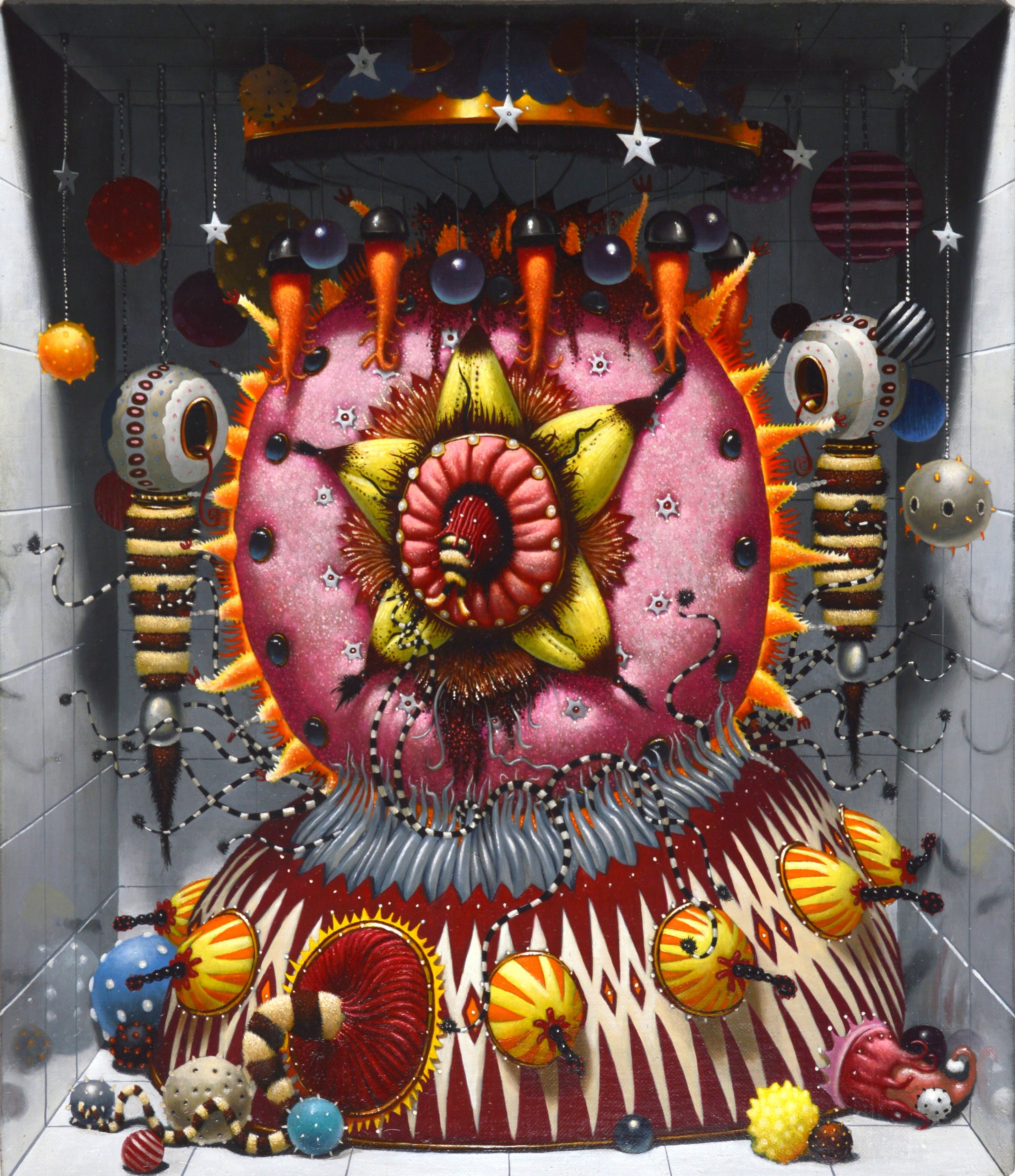 Colorful, three-dimensional art installation with large, abstract shapes and patterns, including a central yellow and red figure, surrounded by striped, dotted, and spiked spherical elements, and hanging star and sphere decorations. The background is dark with light-colored walls and a tiled floor.