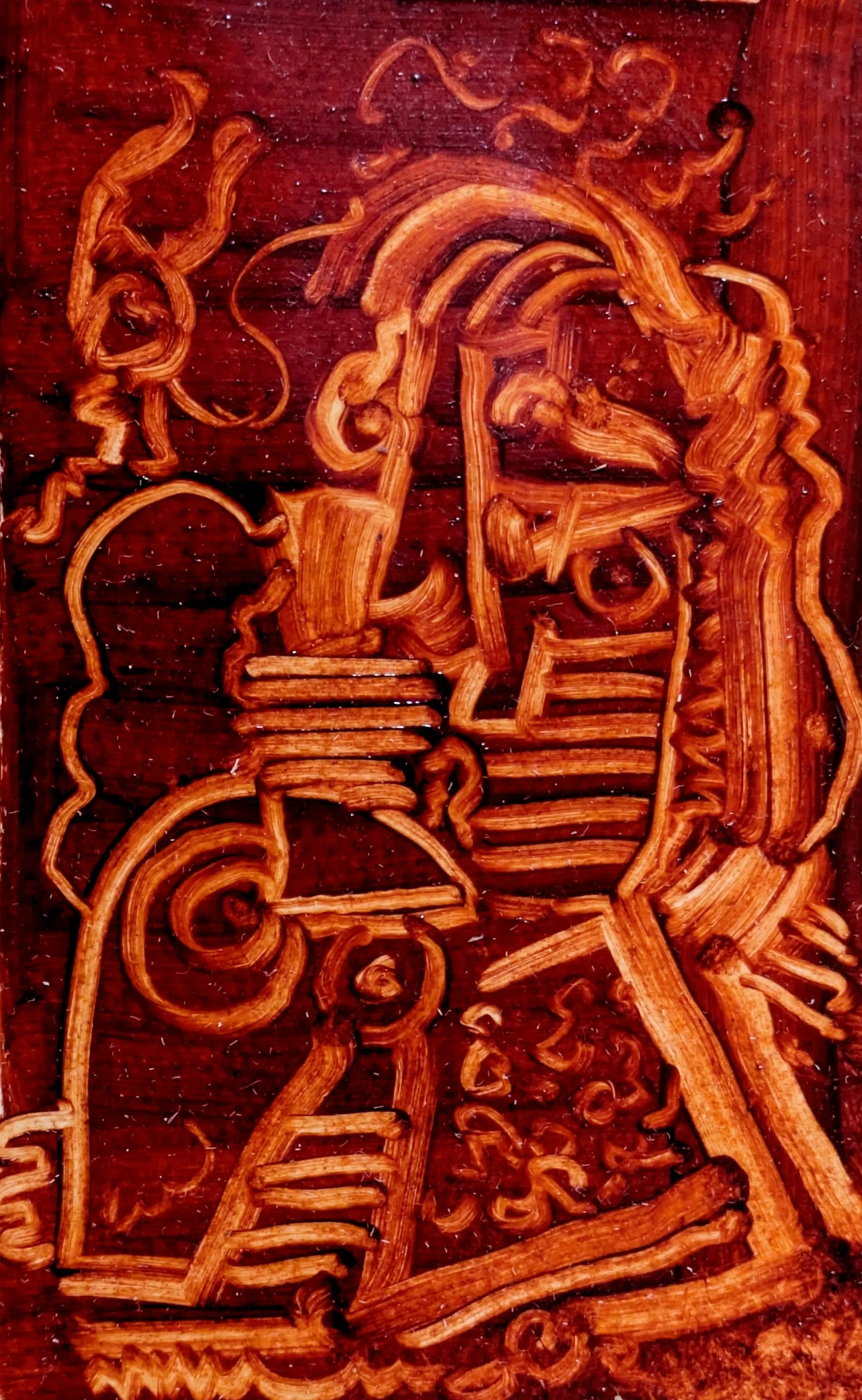 Wooden carving depicting a side profile of two human heads close together, engaged in conversation.