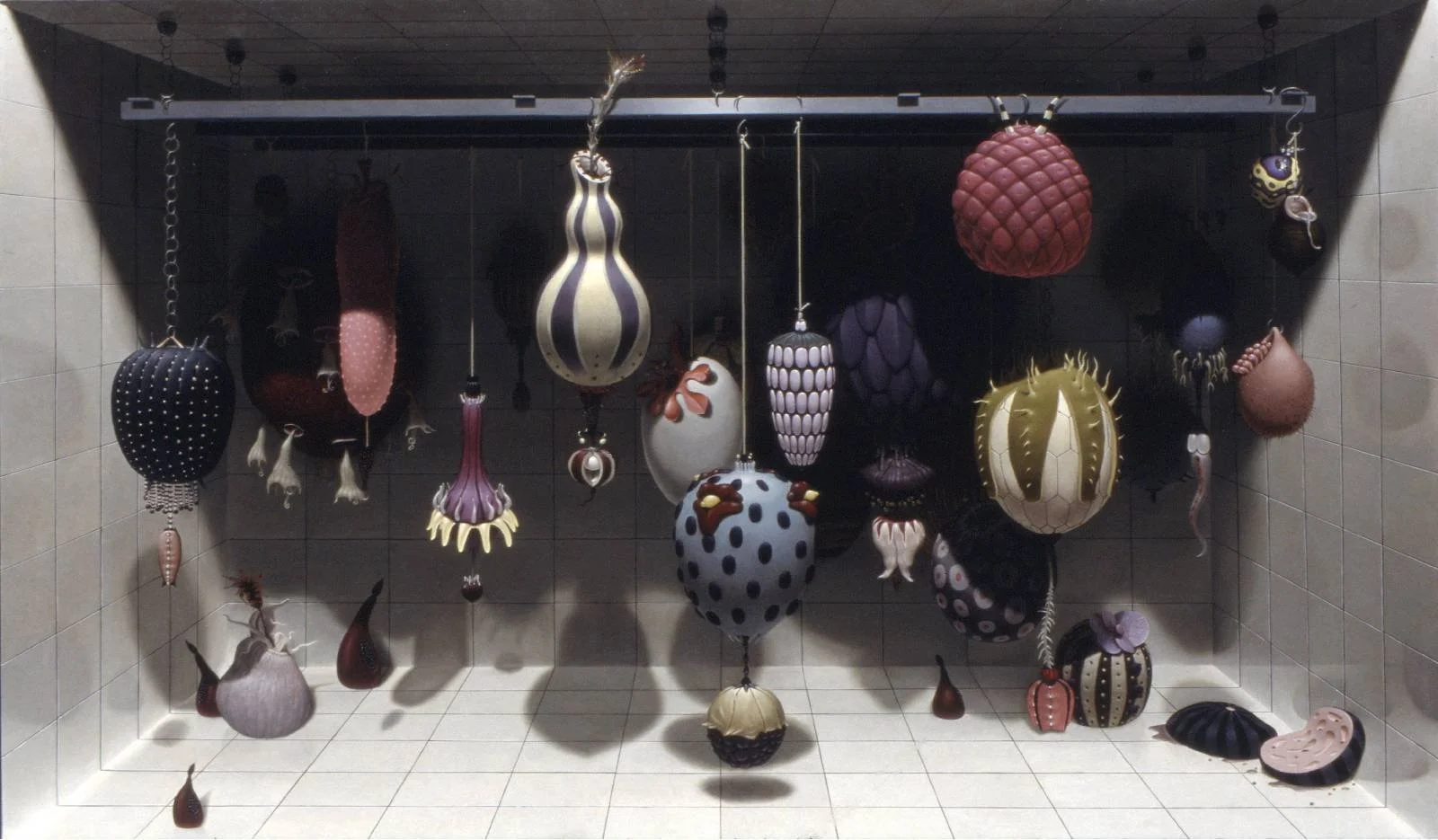 Suspended colorful, abstract designer lamps hanging from a metal rod in a room with tiled walls and floor.