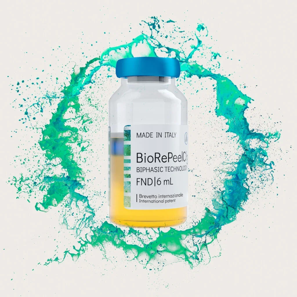 A small glass vial labeled 'BioRePeelCl3' with a blue cap, surrounded by splash of teal and green paint on a light background.