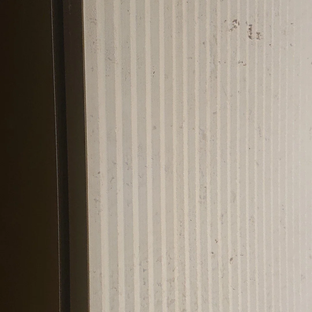 Close-up of a wall with light-colored striped wallpaper and a dark brown door frame.