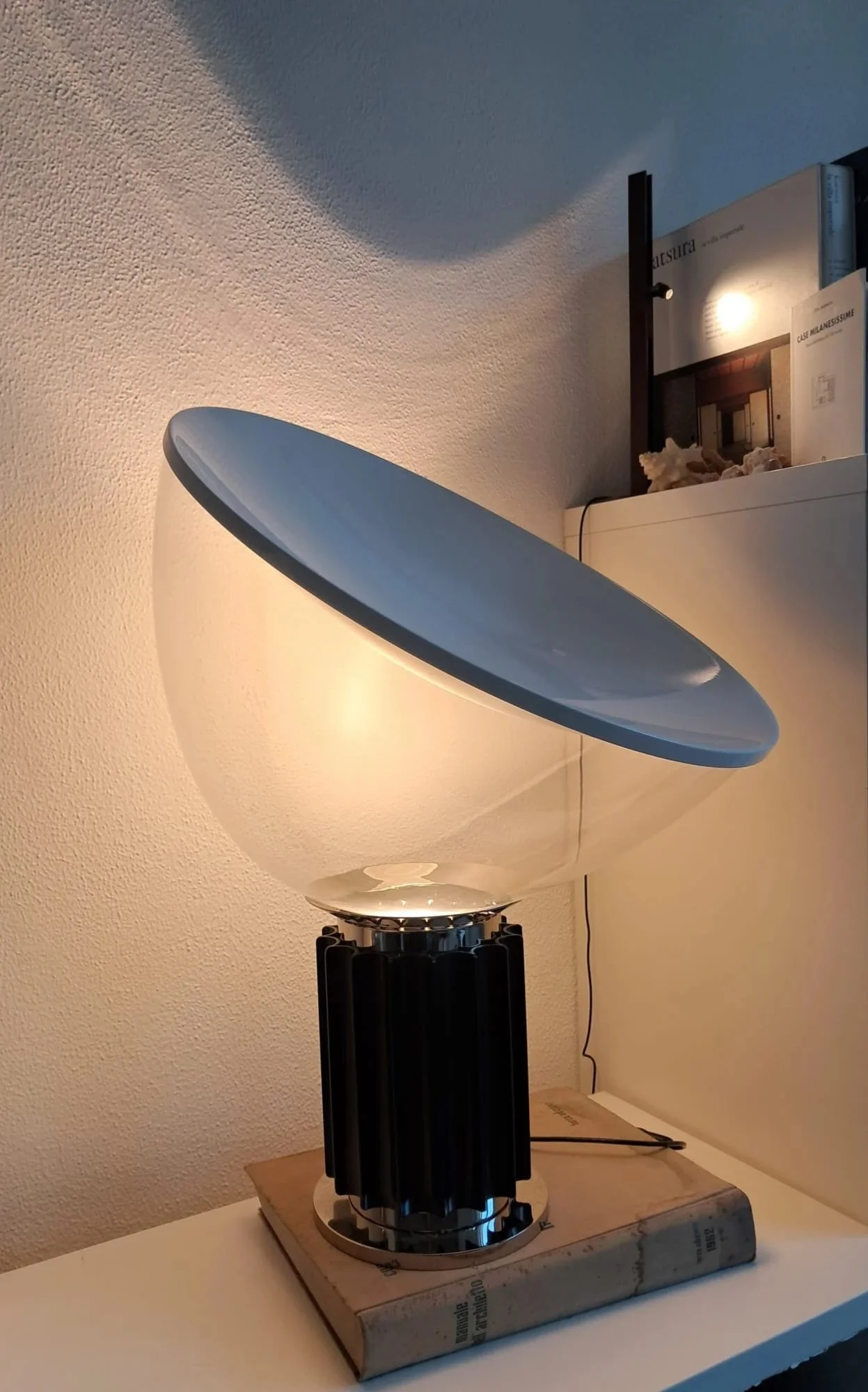 Modern table lamp with a large, spherical glass shade and a black, ribbed base, placed on a wooden surface.