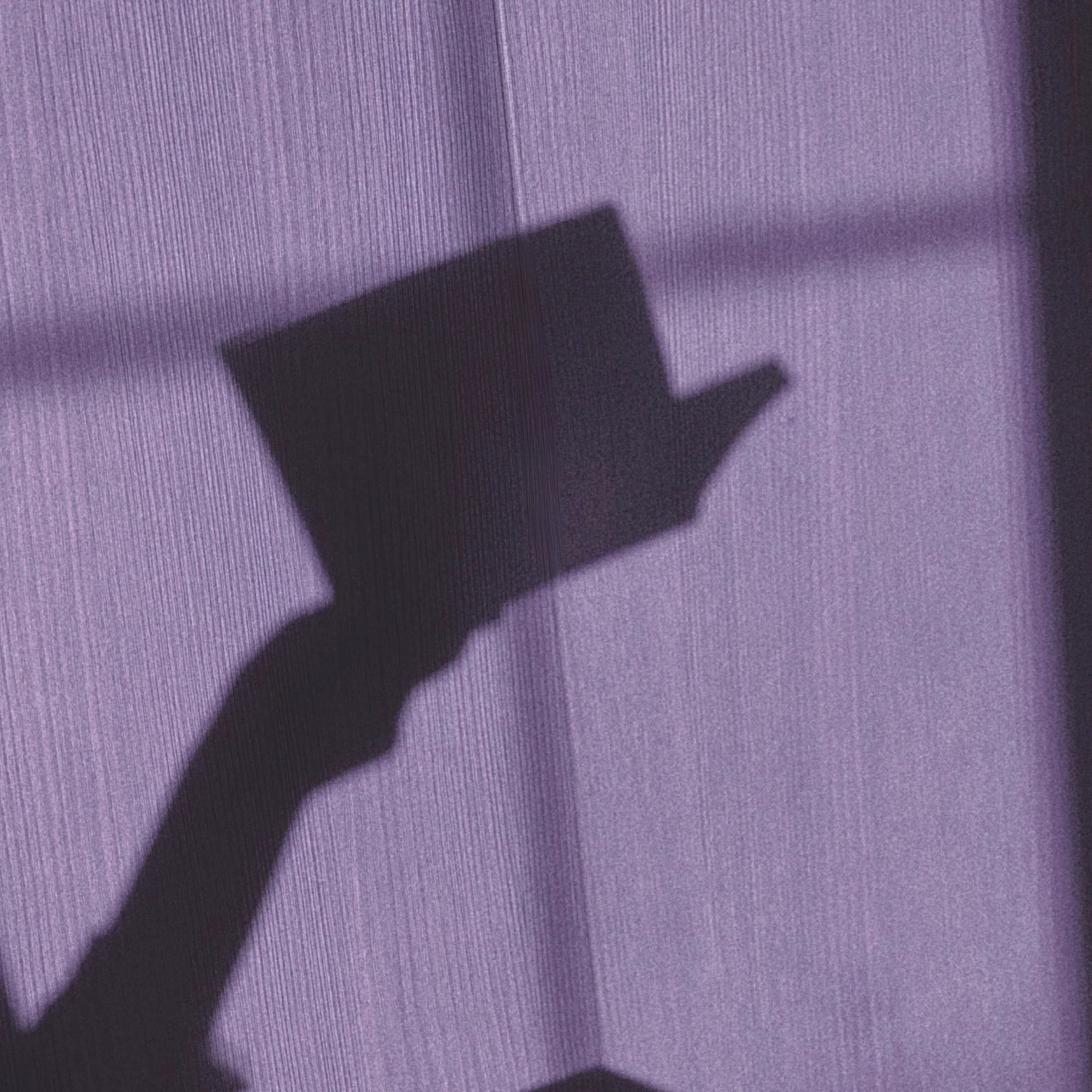 Shadow of a rectangular object on a purple textured surface.