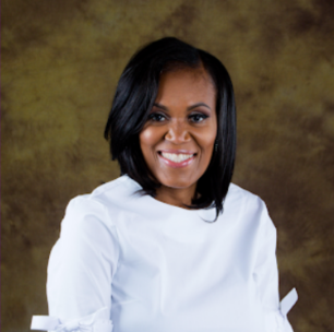 Portrait of a smiling woman with shoulder-length black hair, wearing a white top, against a gold-toned background.