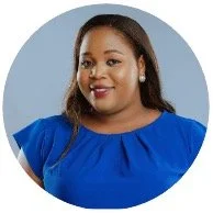 Portrait of a woman with long dark hair wearing a blue top, smiling against a light blue background.