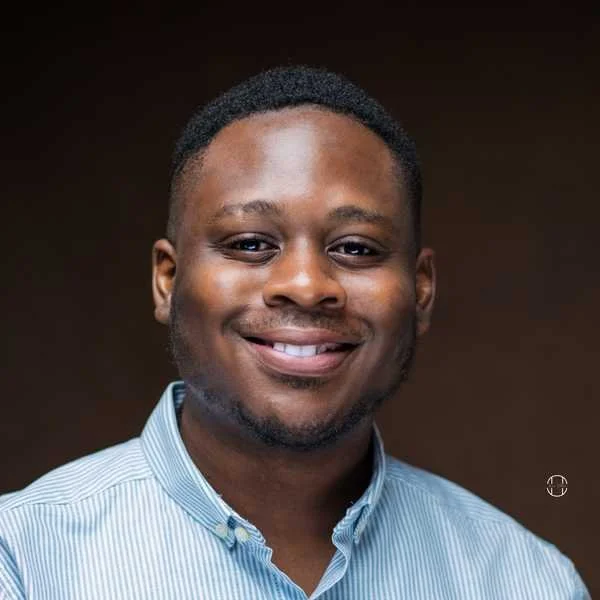 Smiling man with short black hair wearing a light blue dress shirt