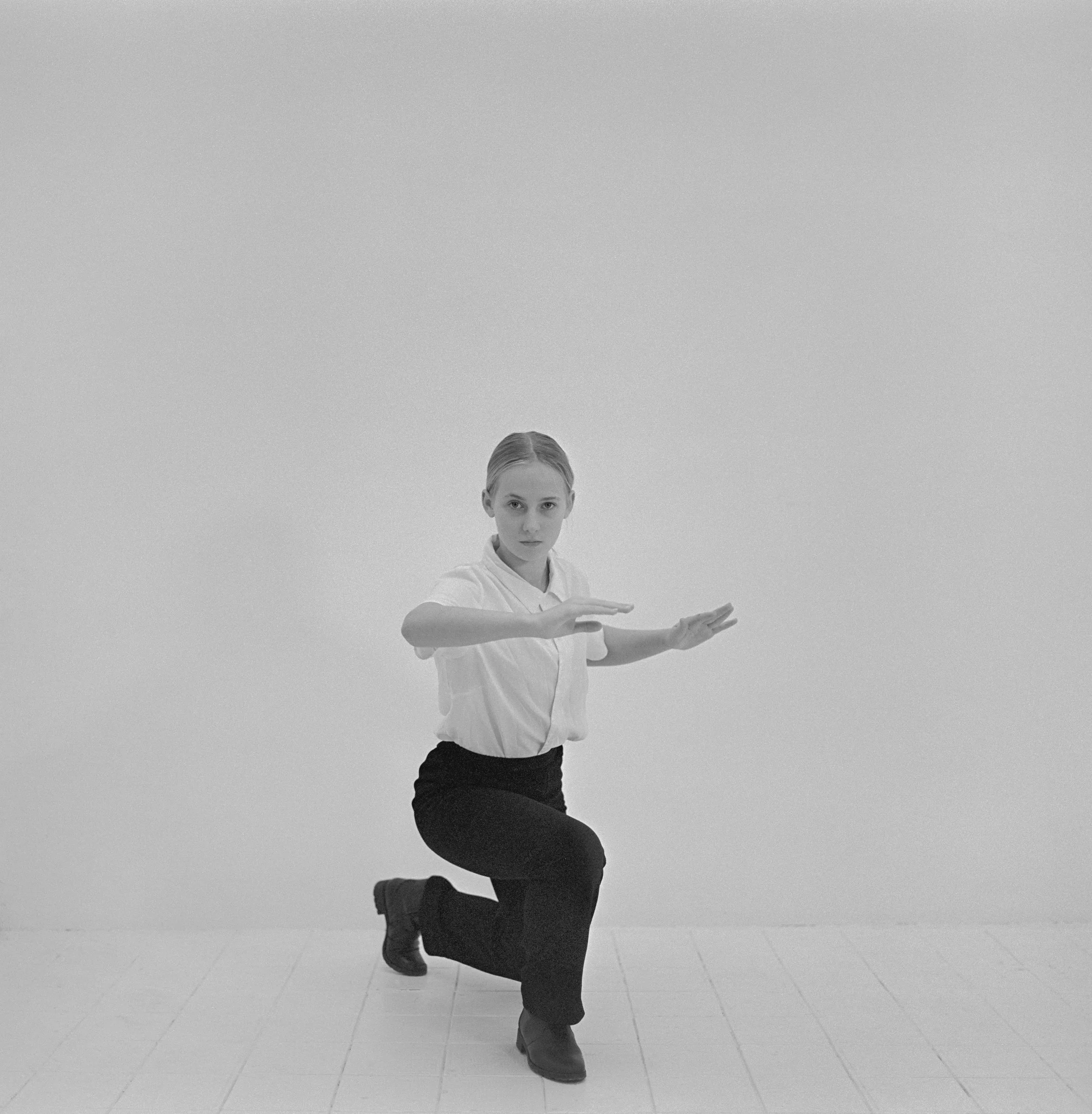 Jeune fille réalisant un geste d'autodéfense dans un studio, photographie argentique noir et blanc de Lucie Belarbi.