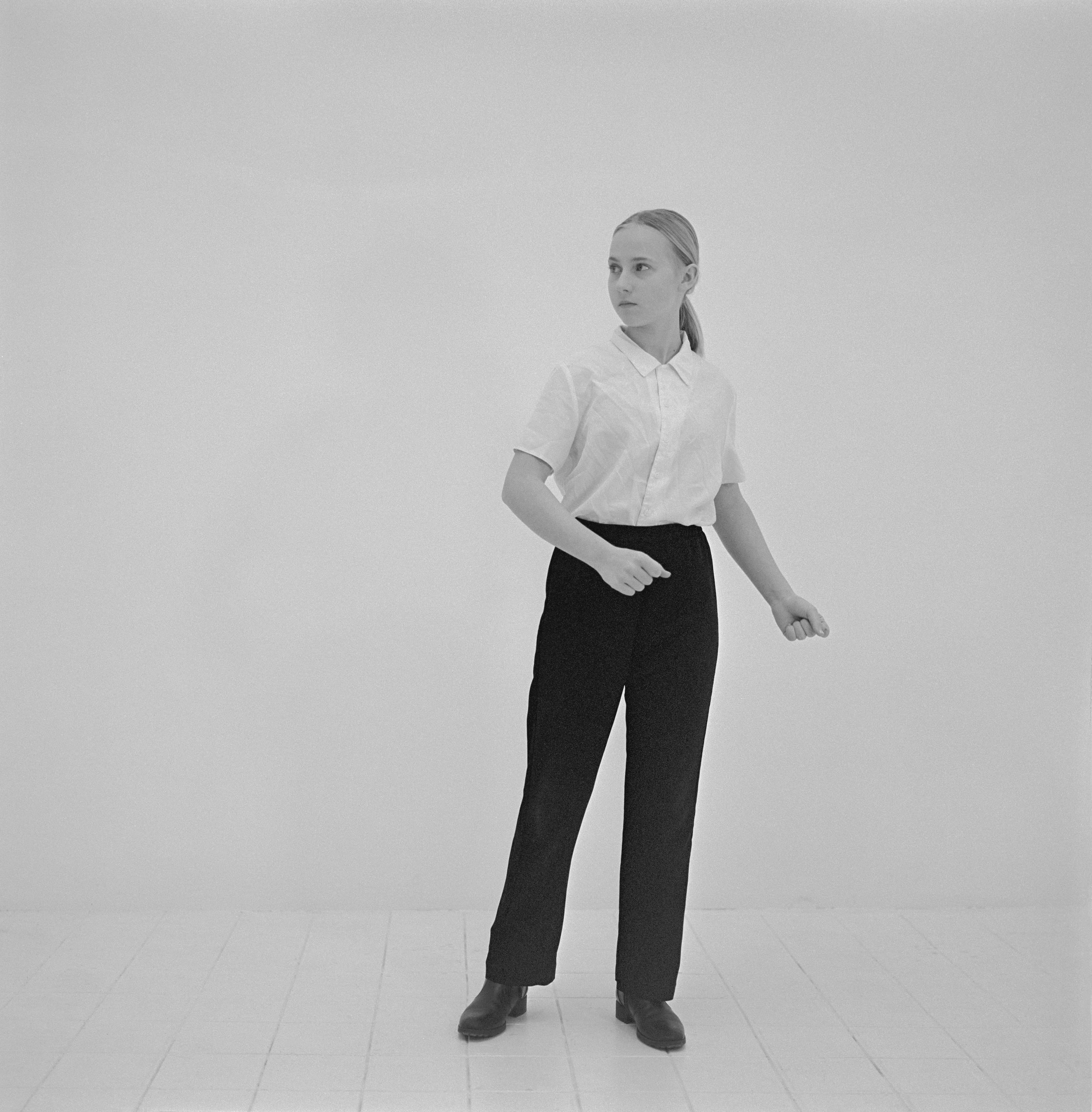 Jeune fille réalisant un geste d'autodéfense dans un studio, photographie argentique noir et blanc de Lucie Belarbi.