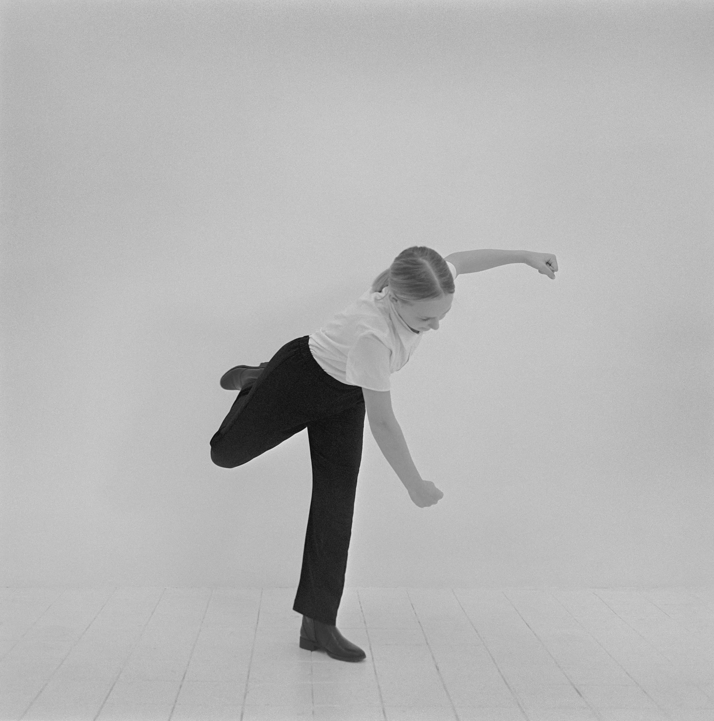 Jeune fille réalisant un geste d'autodéfense dans un studio, photographie argentique noir et blanc de Lucie Belarbi.