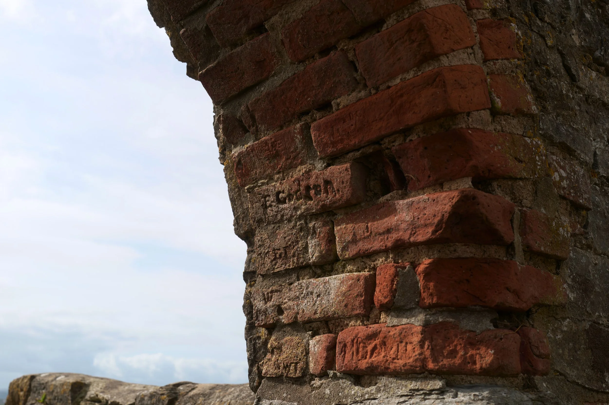 Close-up of an old brick and stone wall against a cloudy sky.