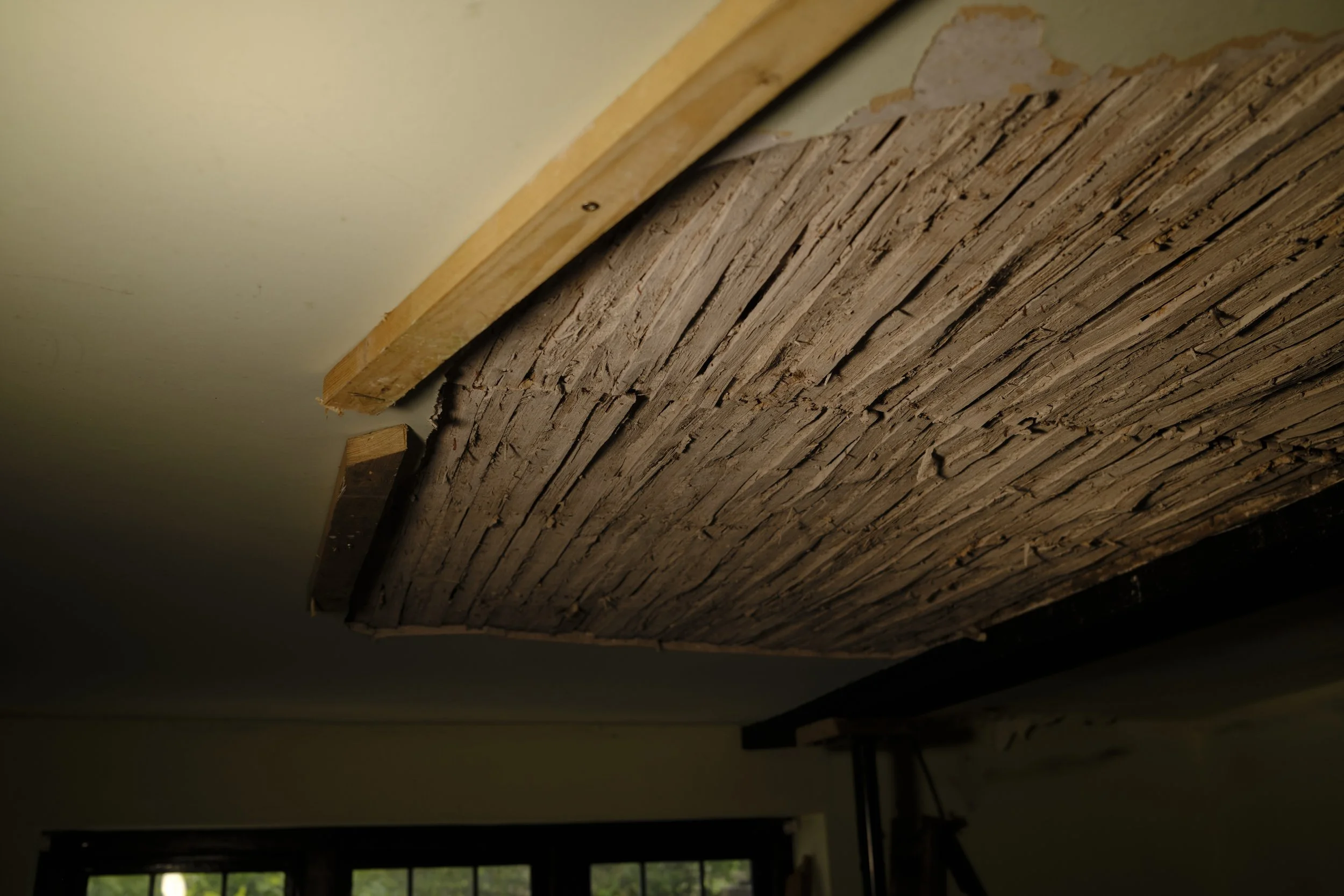 Interior ceiling installation with exposed wood and drywall.