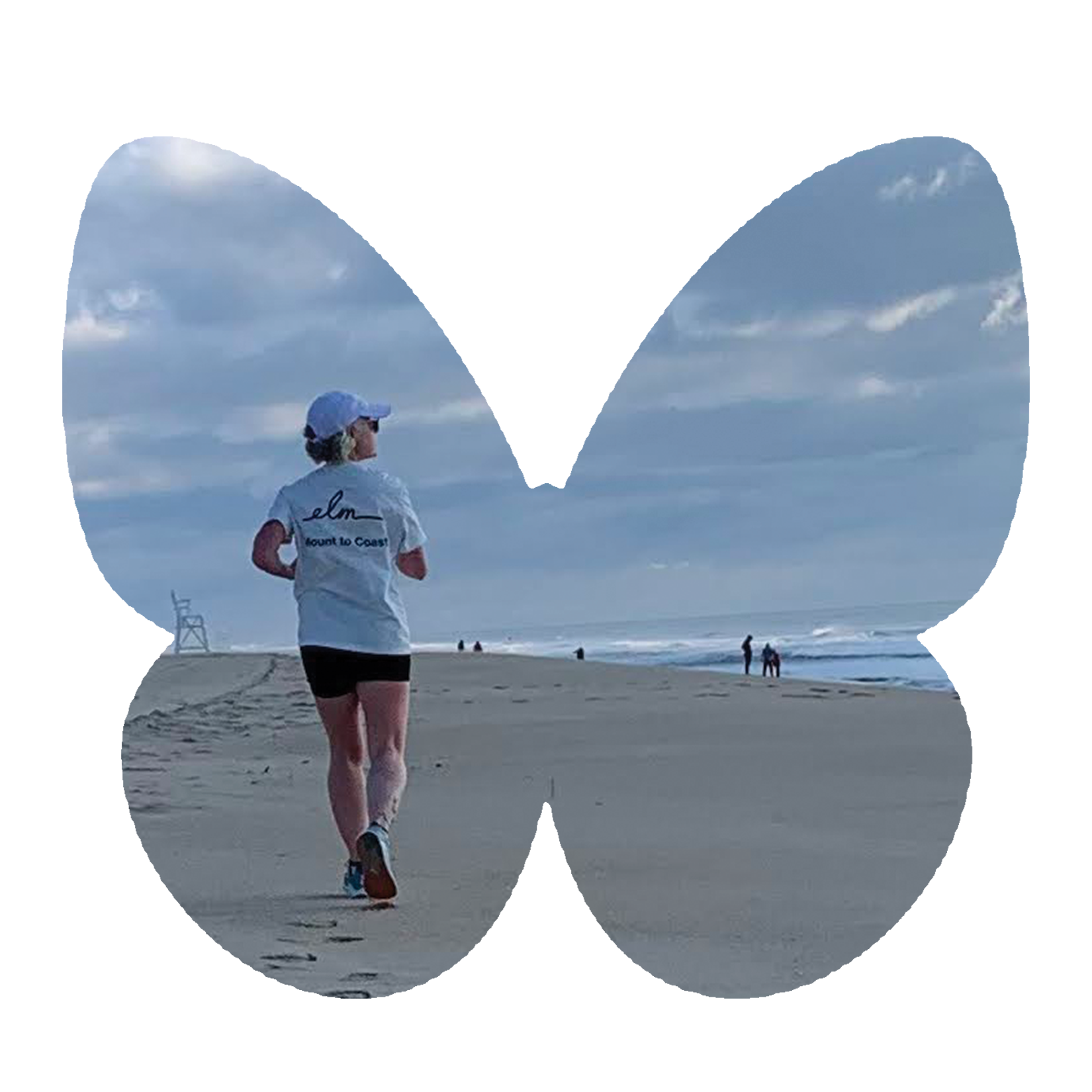 A woman jogging on a beach with cloudy sky, wearing a white cap and a t-shirt with 'Elm' and 'Mount to Coast' printed on the back, leaving footprints in the sand near the ocean.