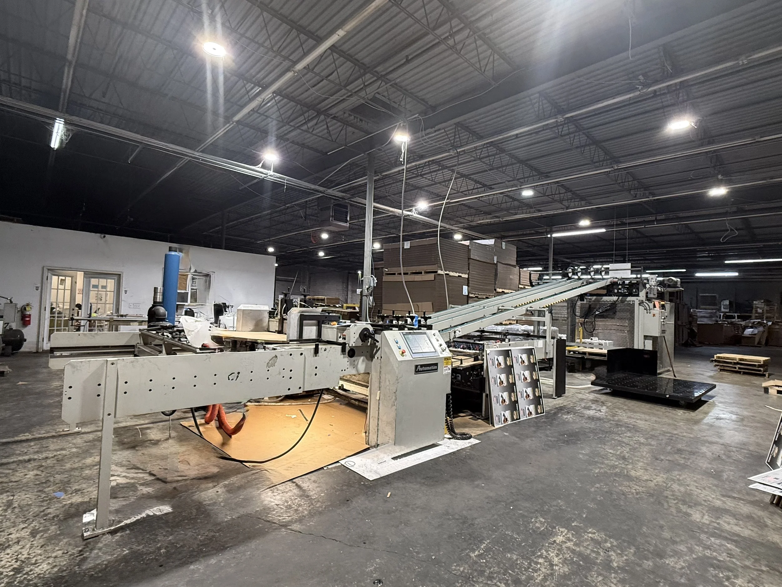 Industrial manufacturing factory with machinery, conveyor belts, and storage shelves in a large warehouse. label mounting, automatan