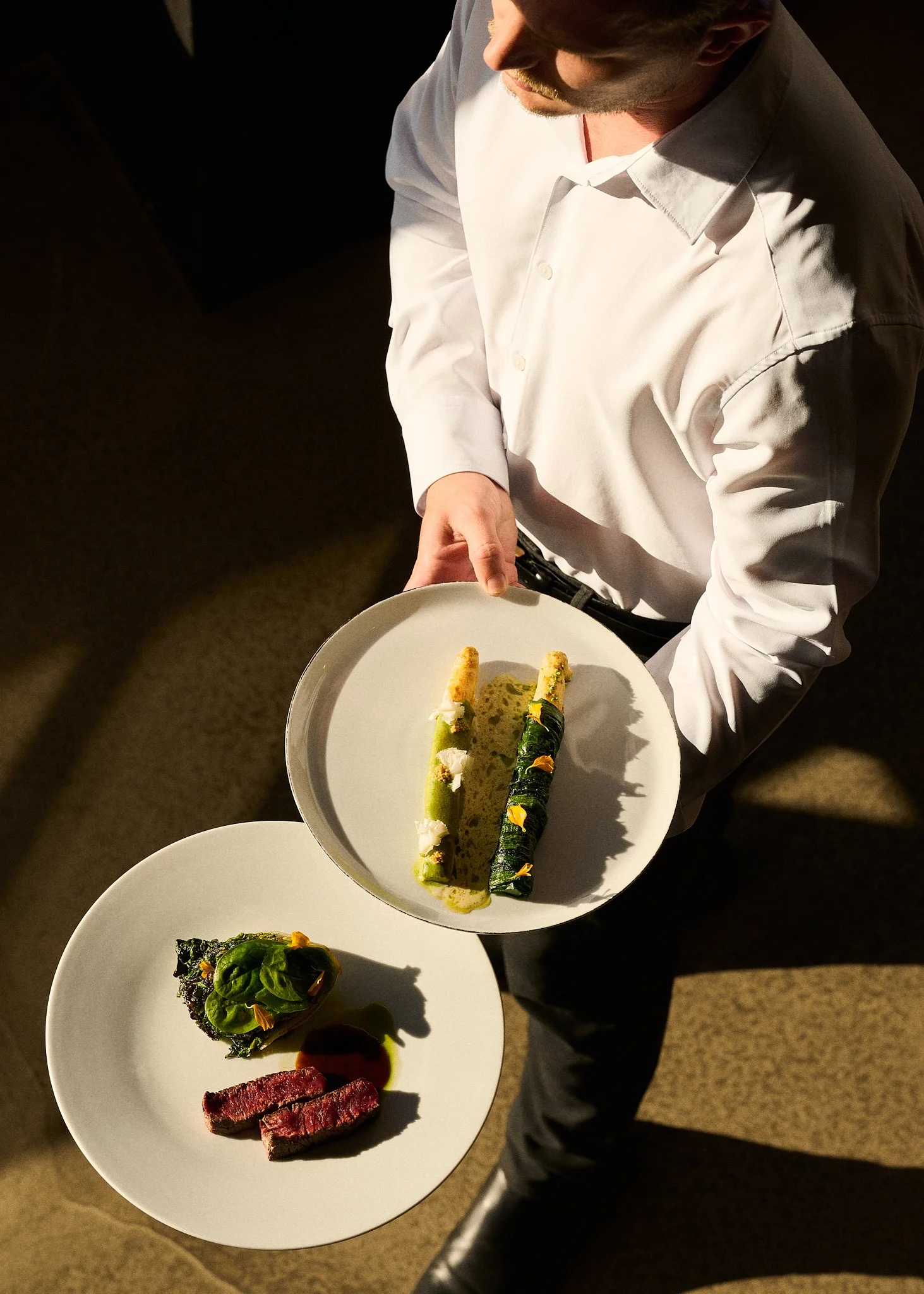 Un serveur tient deux assiettes, dont un plat végétarien. En arrière-plan, on voit le sol.
