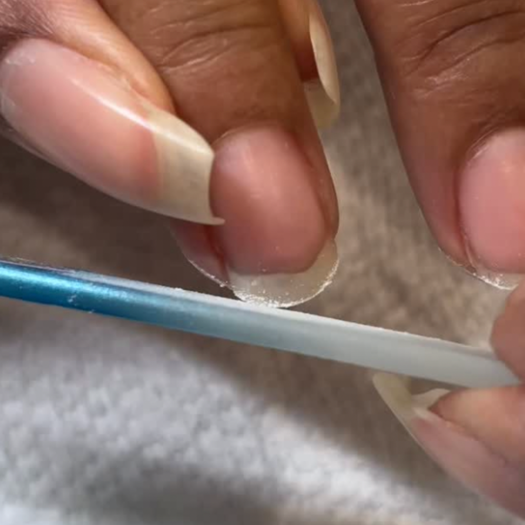 This is a photo of a nail strengthening service offered at our organic nail spa. Right now the client's nail is being filed with a blue glass nail file.