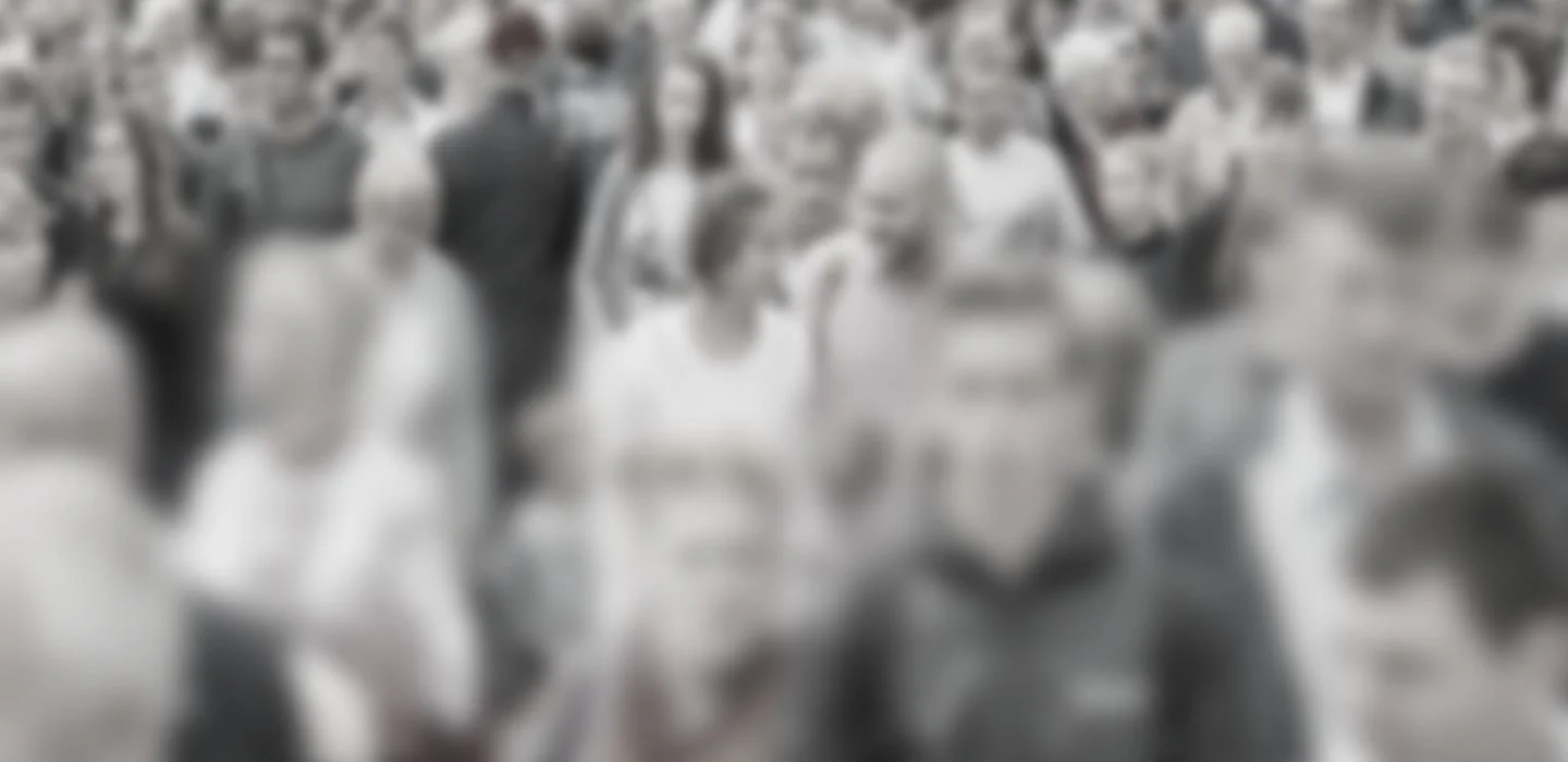 A large crowd of people gathered in an outdoor area, many wearing white clothing and hats.