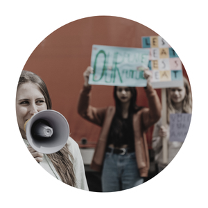 Group of young women holding protest signs and a megaphone, participating in a demonstration.